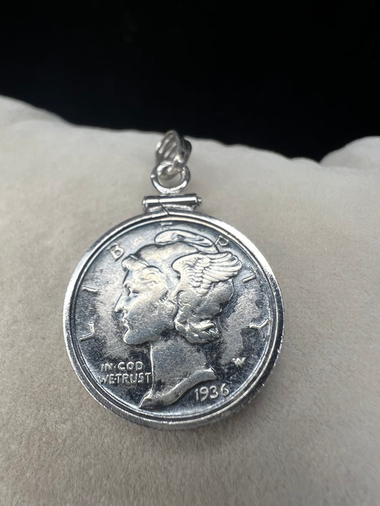 This pendant features a genuine 1936 silver Liberty Head dime, elegantly framed in sterling silver with a matching bail. It is a timeless accessory that combines historical charm with refined craftsmanship.