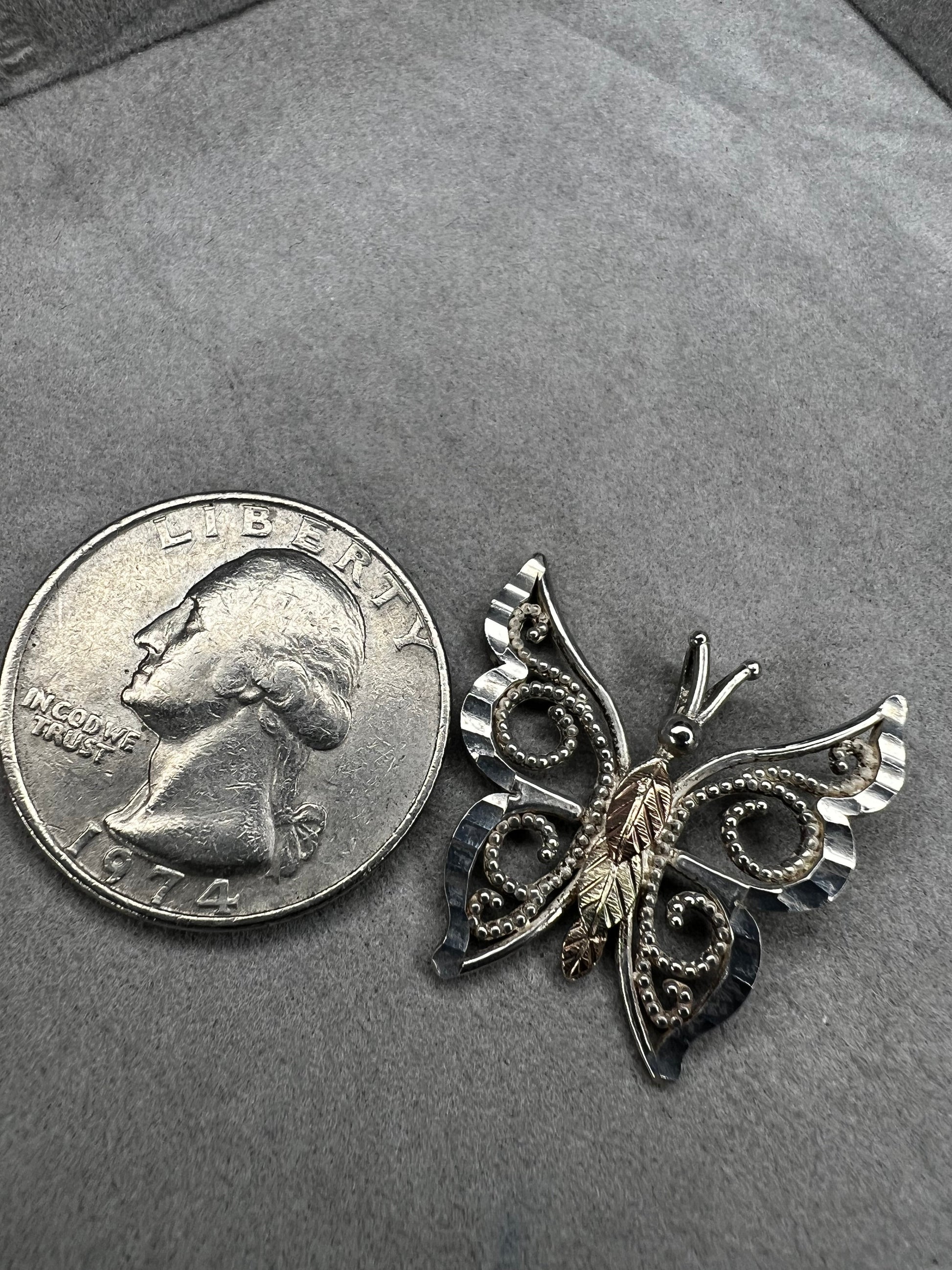 This vintage butterfly pendant combines the timeless elegance of sterling silver with the rich warmth of 12 karat gold. Signed C. Co., this Black Hills Gold piece is perfect for those who appreciate classic craftsmanship with a touch of sophistication.