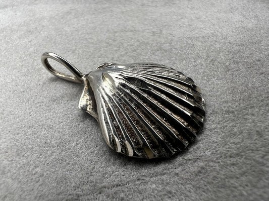 This vintage scallop shell pendant is expertly crafted from sterling silver, offering a timeless accessory. Its delicate size and classic design make it an ideal piece to pair with a small chain, adding subtle elegance to any outfit while celebrating a love for the beach or sea.