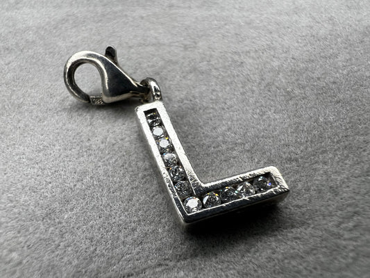 This Thomas Sabo sterling silver charm features the initial "L" elegantly adorned with sparkling cubic zirconia stones. This piece adds a subtle yet distinctive touch for anyone whose name begins with "L."