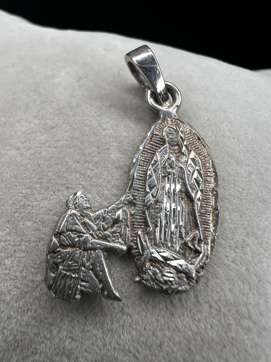 Crafted from sterling silver, this pendant shows a figure kneeling before another, suggestive of a religious deity. This piece is detailed with diamond cuts to catch the light.
