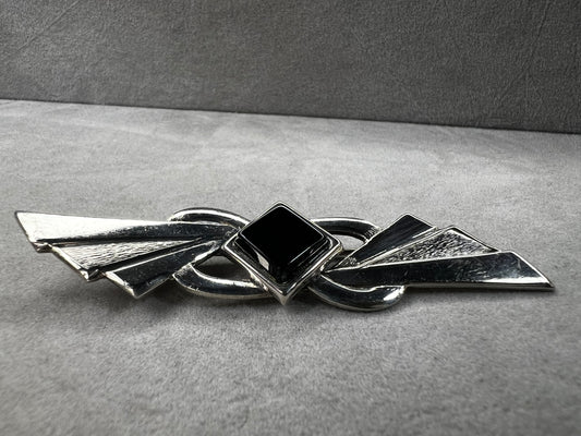 This vintage brooch is crafted from 800 silver and features a striking black diamond-shaped Jet centerpiece. Its classic design adds a sophisticated vintage touch to any outfit.