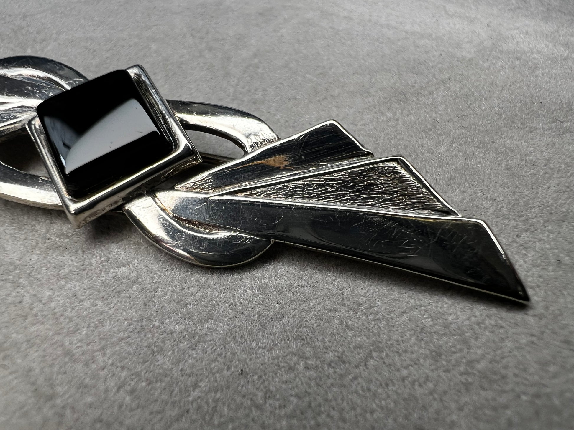 This vintage brooch is crafted from 800 silver and features a striking black diamond-shaped Jet centerpiece. Its classic design adds a sophisticated vintage touch to any outfit.