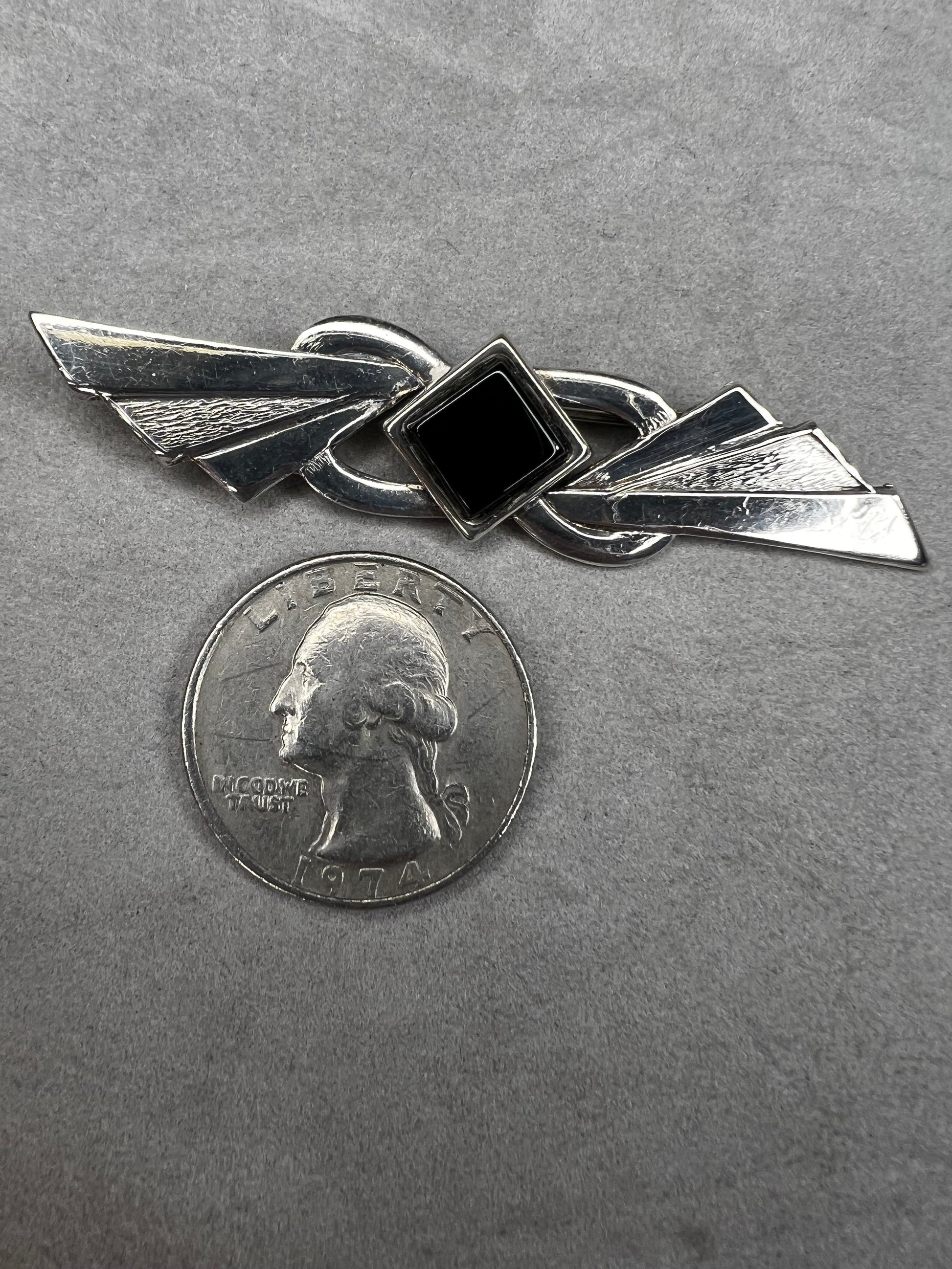 This vintage brooch is crafted from 800 silver and features a striking black diamond-shaped Jet centerpiece. Its classic design adds a sophisticated vintage touch to any outfit.