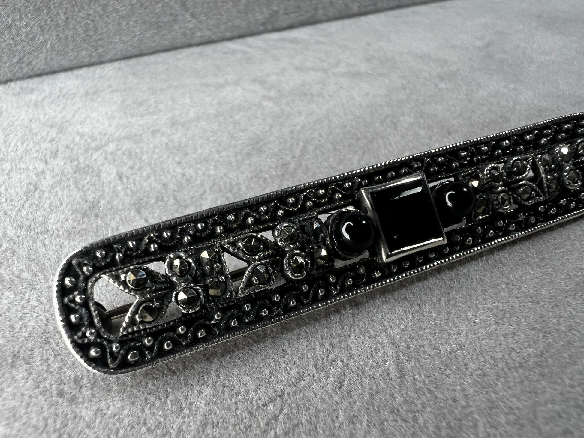 This exquisite 2-inch sterling silver bar brooch features authentic marcasite and jet stones, embodying the timeless elegance of the Art Deco era. It's a distinctive accessory that complements both vintage and modern styles.