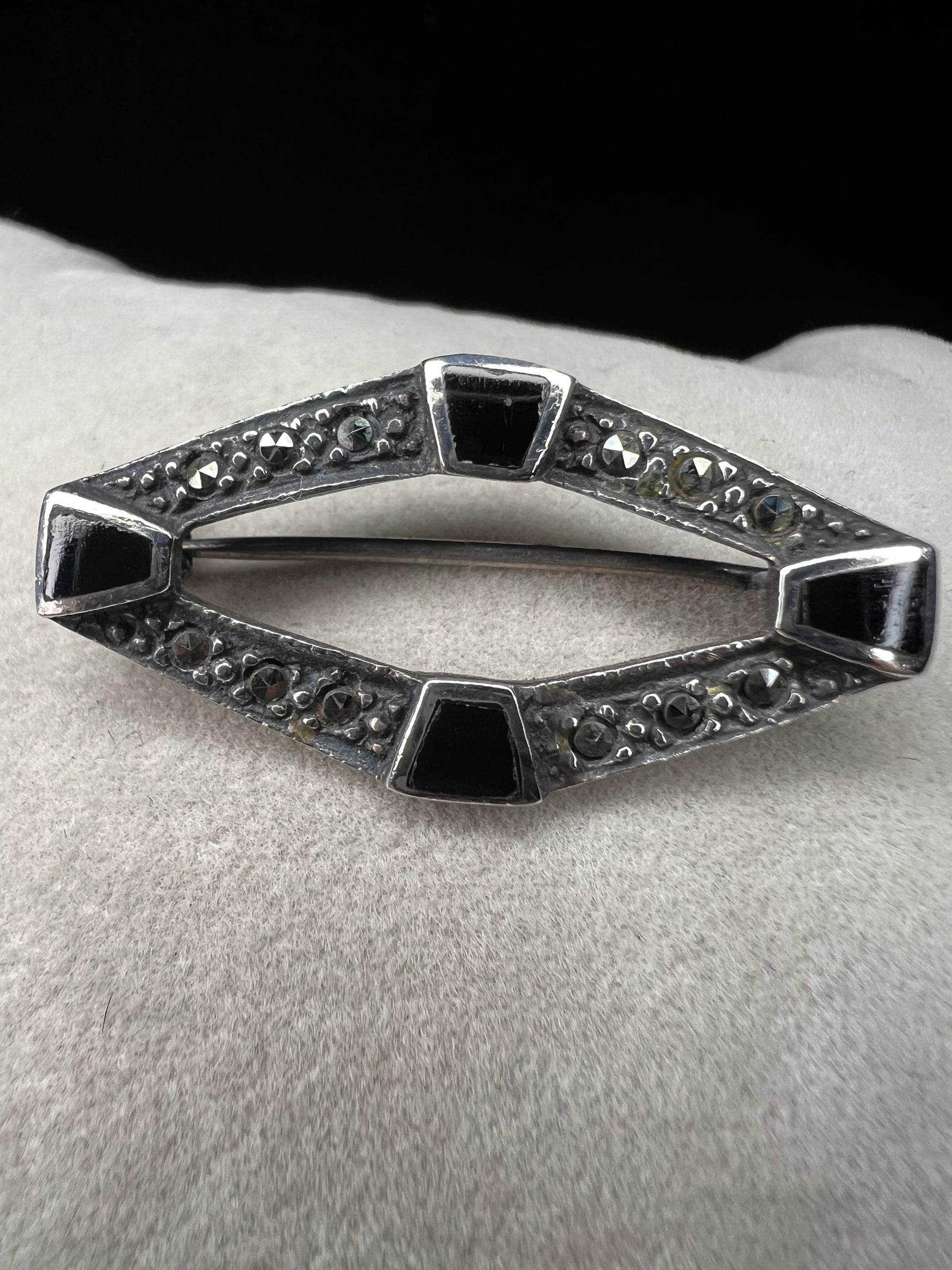 This vintage mid-century brooch combines sterling silver, marcasite, and enamel to create a timeless accessory. Its classic design adds a touch of elegance and history to any jewelry collection.