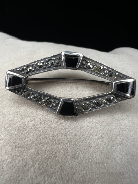 This vintage mid-century brooch combines sterling silver, marcasite, and enamel to create a timeless accessory. Its classic design adds a touch of elegance and history to any jewelry collection.