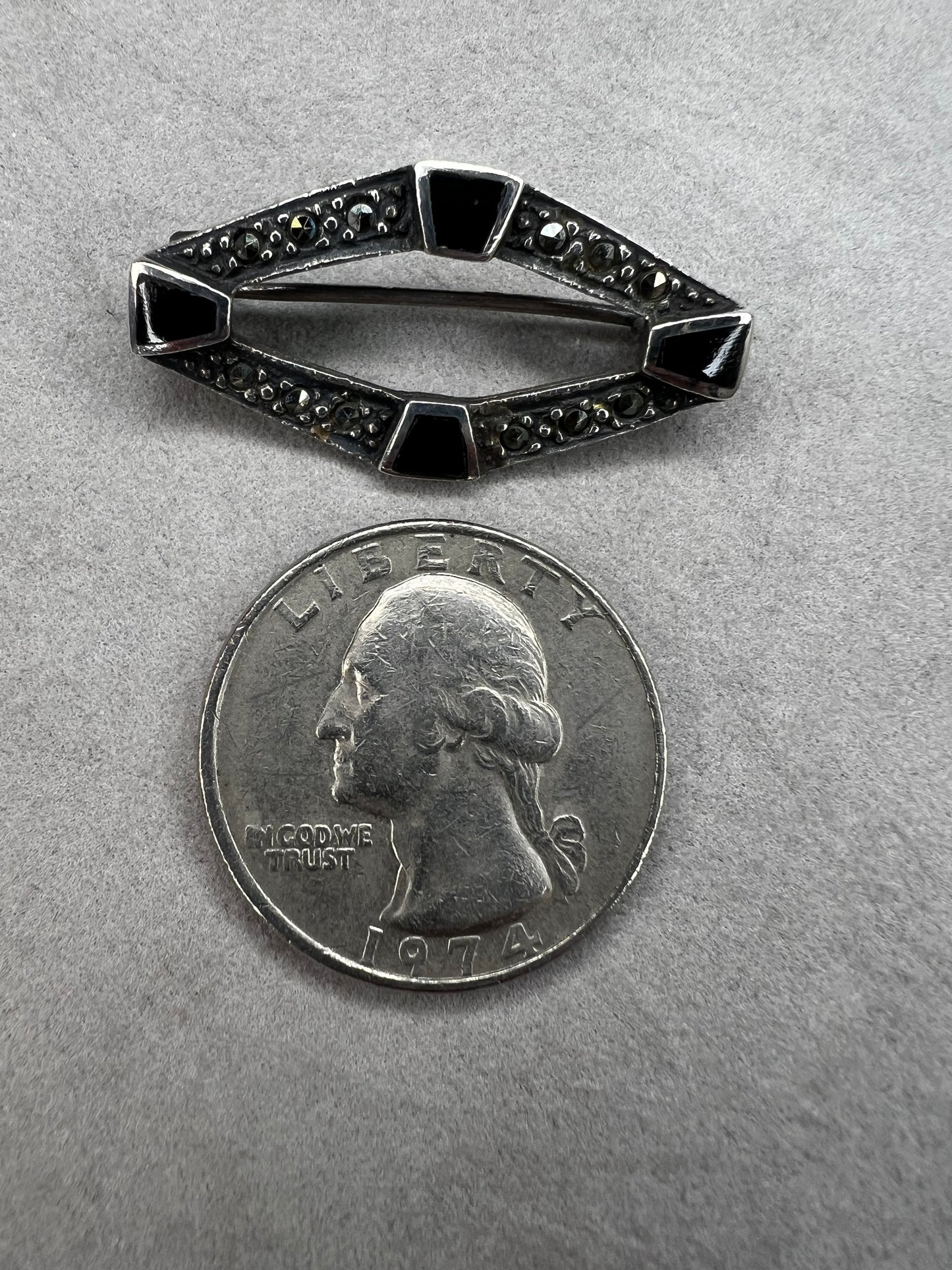 This vintage mid-century brooch combines sterling silver, marcasite, and enamel to create a timeless accessory. Its classic design adds a touch of elegance and history to any jewelry collection.