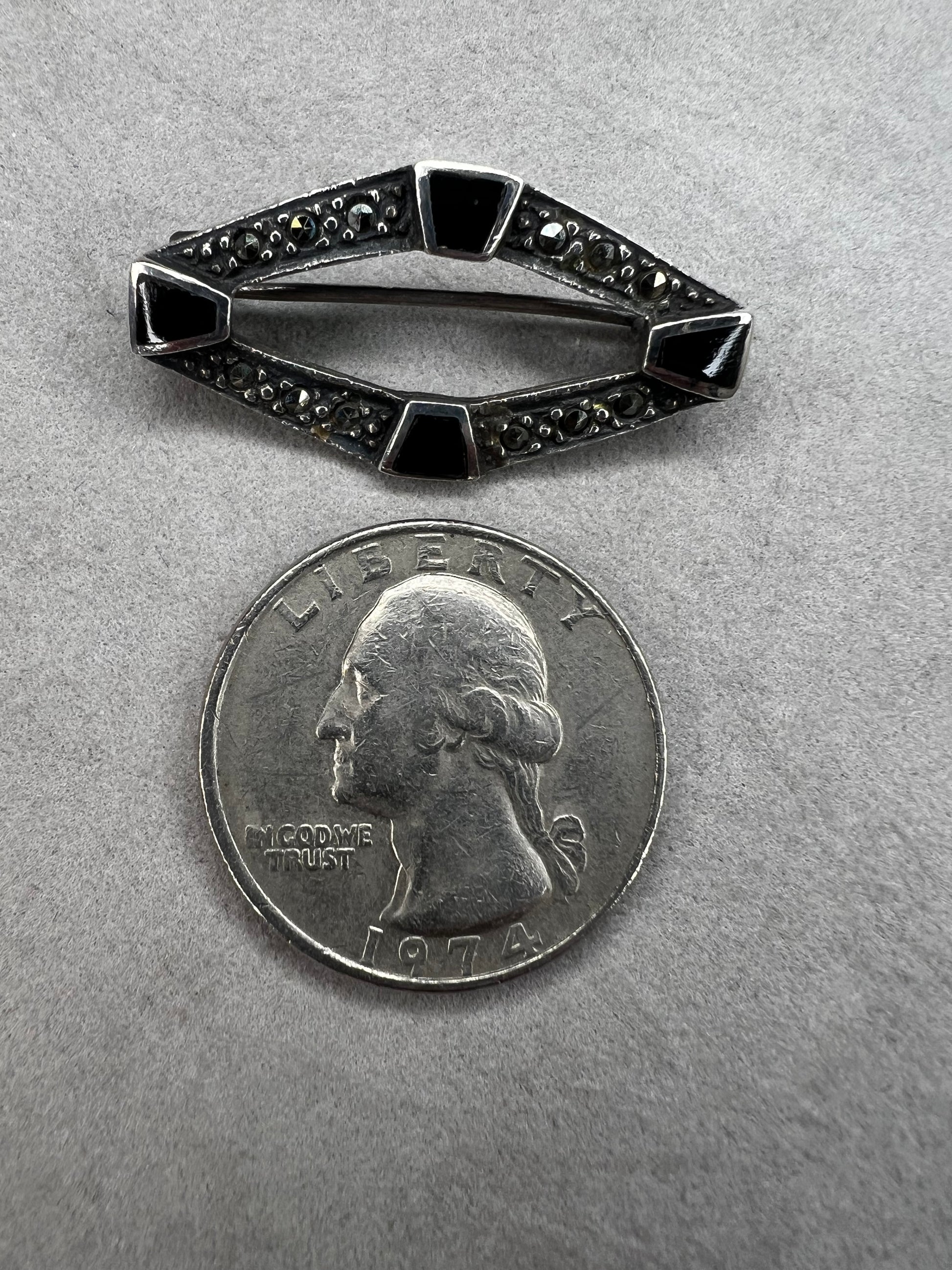 This vintage mid-century brooch combines sterling silver, marcasite, and enamel to create a timeless accessory. Its classic design adds a touch of elegance and history to any jewelry collection.