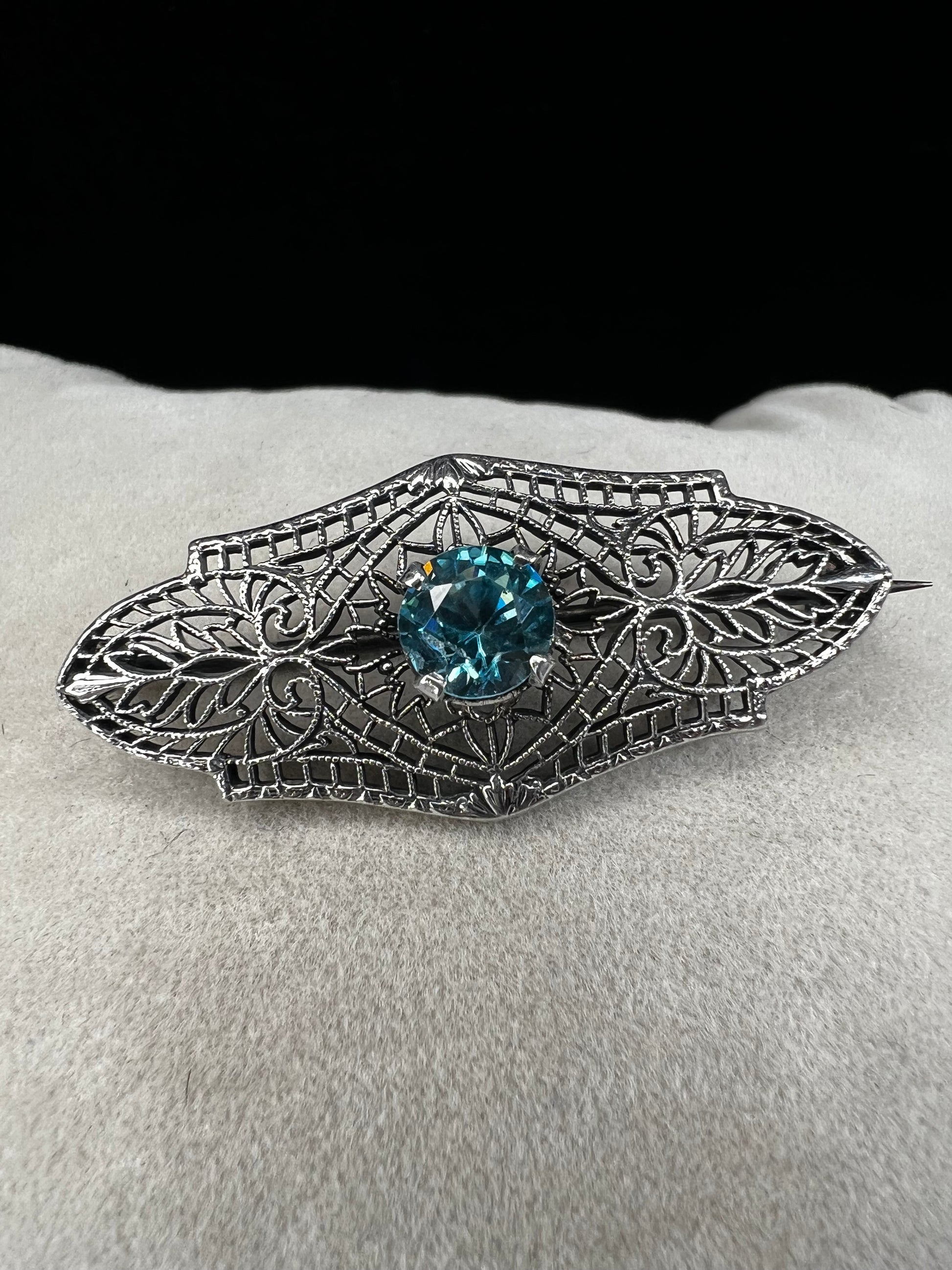 This antique filigree brooch features a beautiful blue topaz set in sterling silver, signed with a distinctive "K." Measuring 1.5 inches, it offers a delicate and elegant touch to any jewelry collection. Perfect for adding a vintage charm to your style.