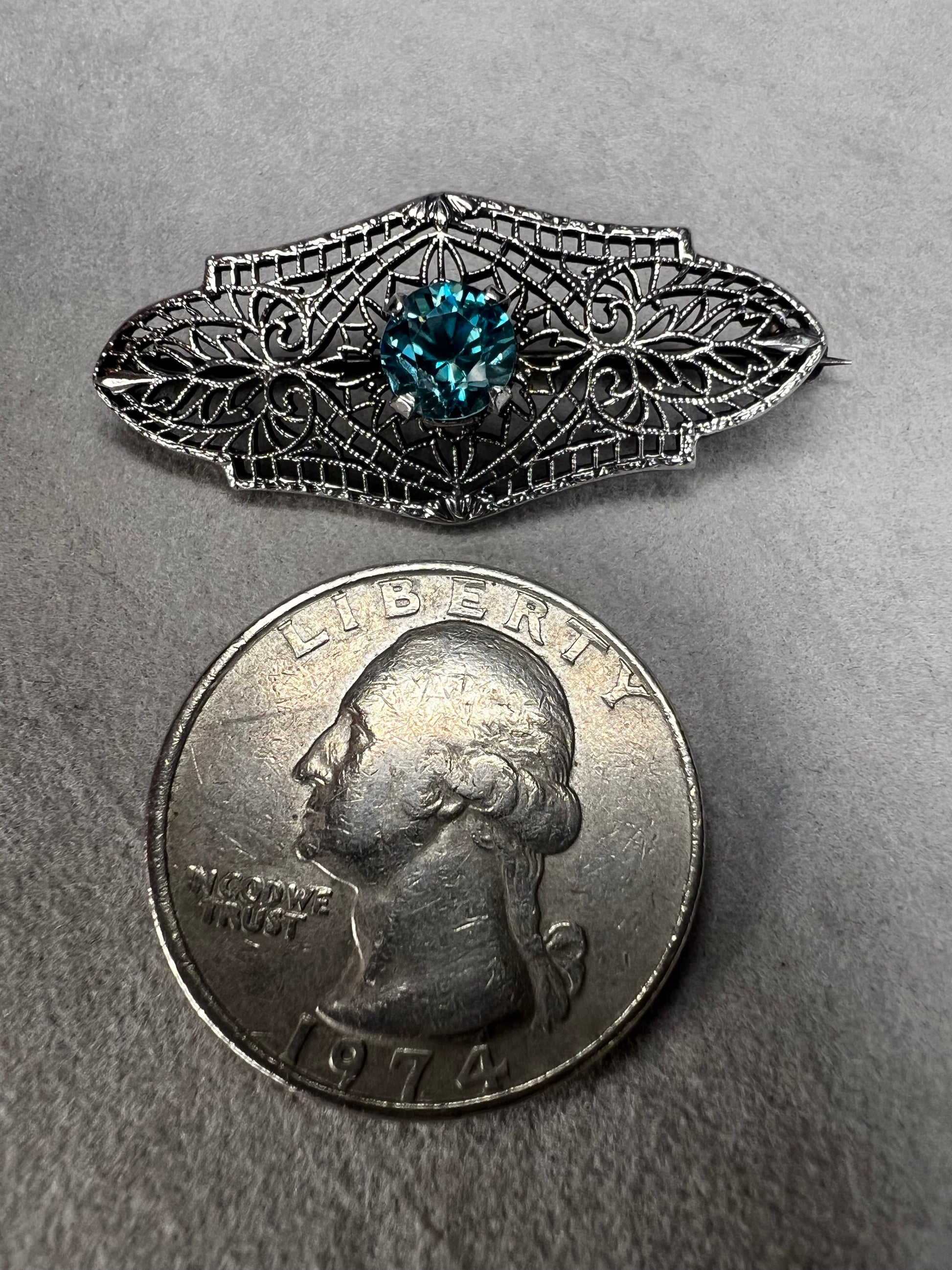 This antique filigree brooch features a beautiful blue topaz set in sterling silver, signed with a distinctive "K." Measuring 1.5 inches, it offers a delicate and elegant touch to any jewelry collection. Perfect for adding a vintage charm to your style.