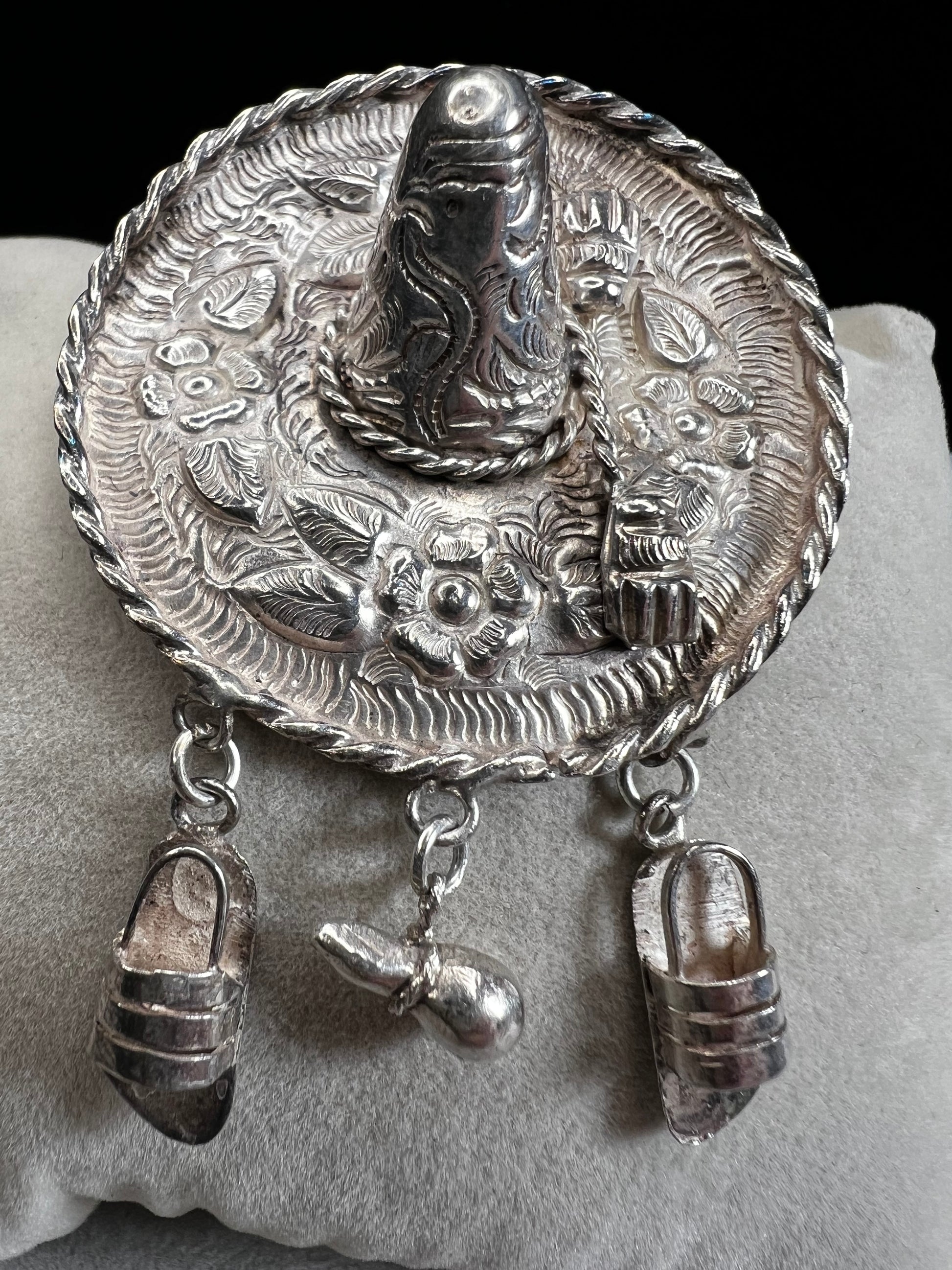 This charming 1950s sterling silver brooch captures a playful scene with a large sombrero, a pair of sandals, and a maraca. Its unique design reflects vintage character and cultural flair, making it a delightful accessory that adds personality and nostalgia to your collection.