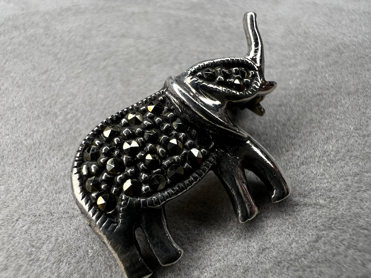 This charming vintage sterling silver elephant brooch features delicate marcasite accents that catch the light beautifully. Measuring 1 inch, it’s a subtle yet elegant accessory that adds a touch of sparkle and personality to any outfit.