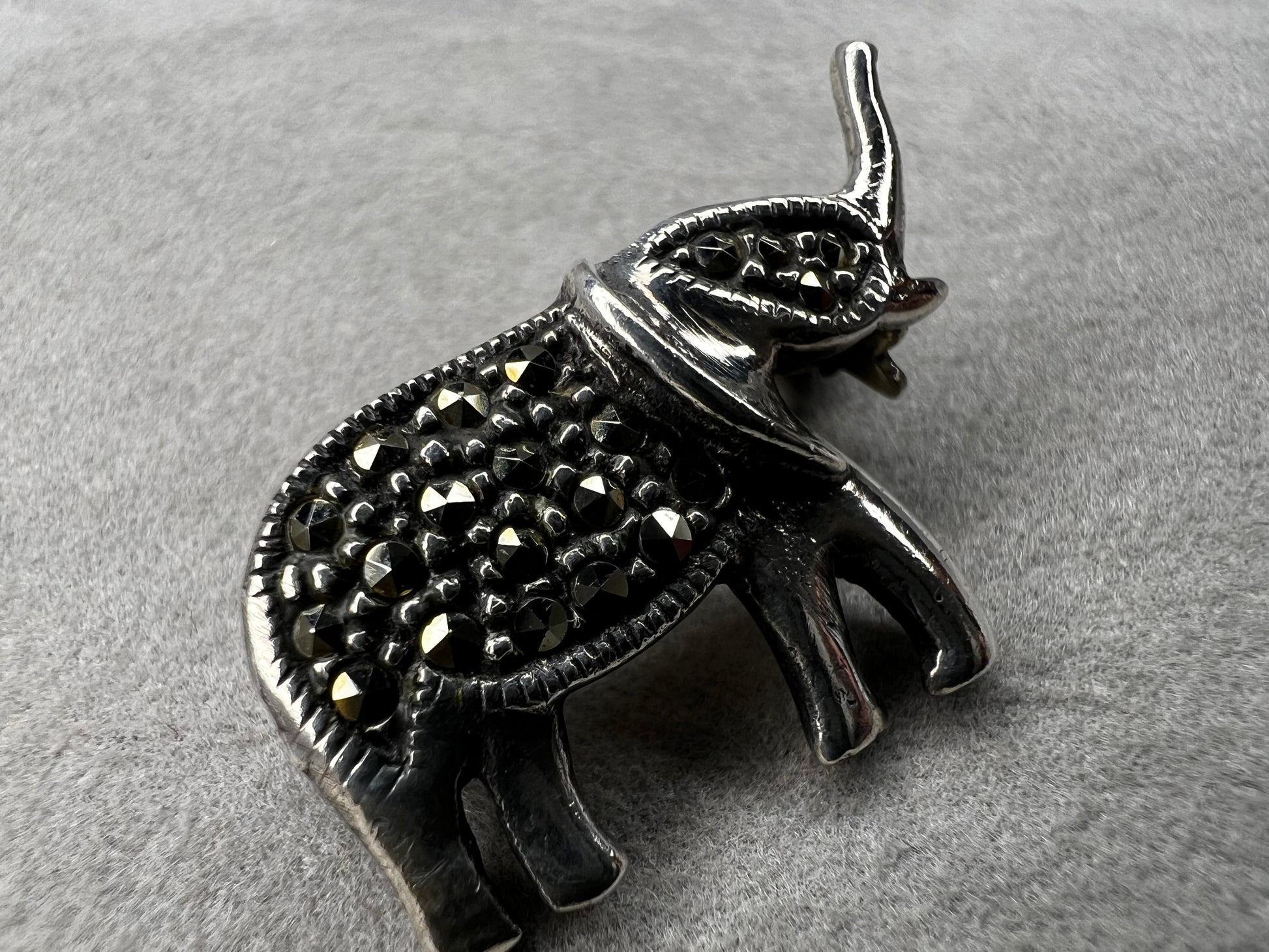 This charming vintage sterling silver elephant brooch features delicate marcasite accents that catch the light beautifully. Measuring 1 inch, it’s a subtle yet elegant accessory that adds a touch of sparkle and personality to any outfit.
