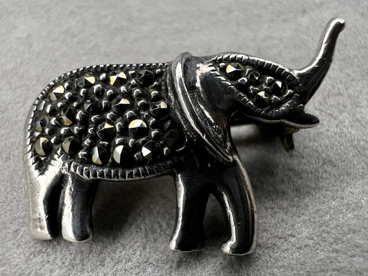 This charming vintage sterling silver elephant brooch features delicate marcasite accents that catch the light beautifully. Measuring 1 inch, it’s a subtle yet elegant accessory that adds a touch of sparkle and personality to any outfit.