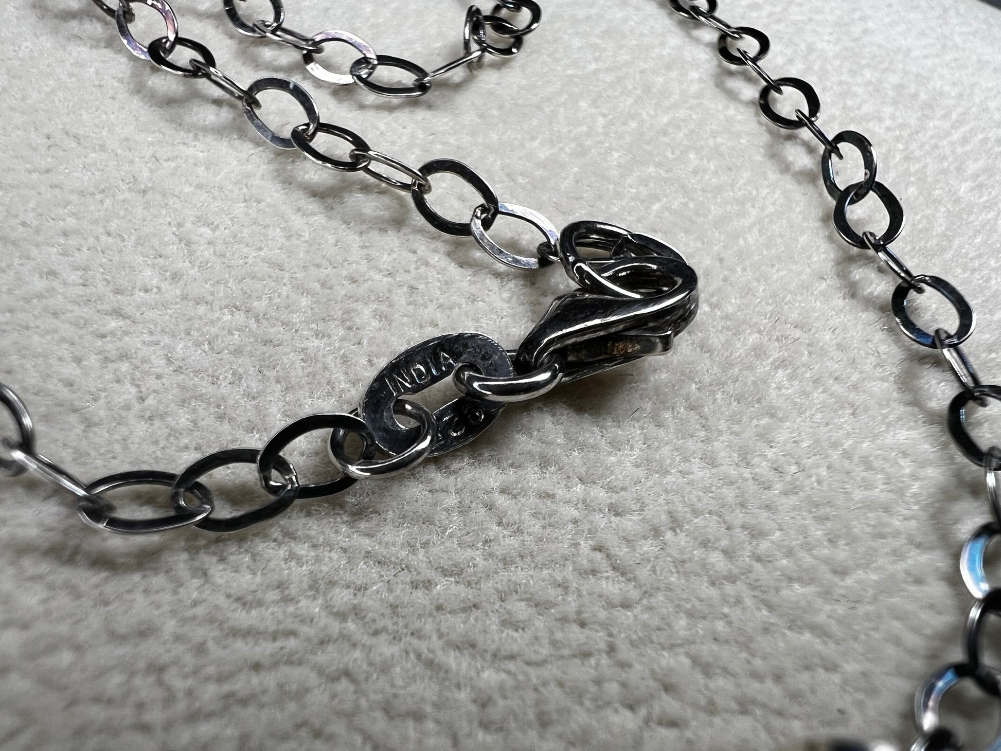 This striking pendant on a chain necklace features a polished Larvikite cabochon, showcasing its distinctive dark gray body with shimmering silver flashes. The stone is set in an artistic sterling silver wirework design, creating a bold and modern statement piece.