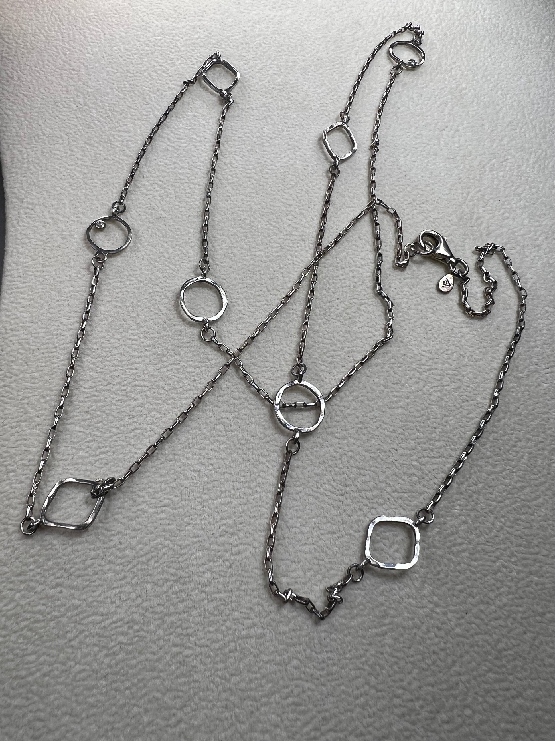 This retired Silpada necklace, measuring 34" in length, is crafted from sterling silver and accented with a few sparkling cubic zirconia stones. This "Ring Around the Rosy" necklace offers a subtle flash of light, making it a charming and elegant addition to any jewelry collection.