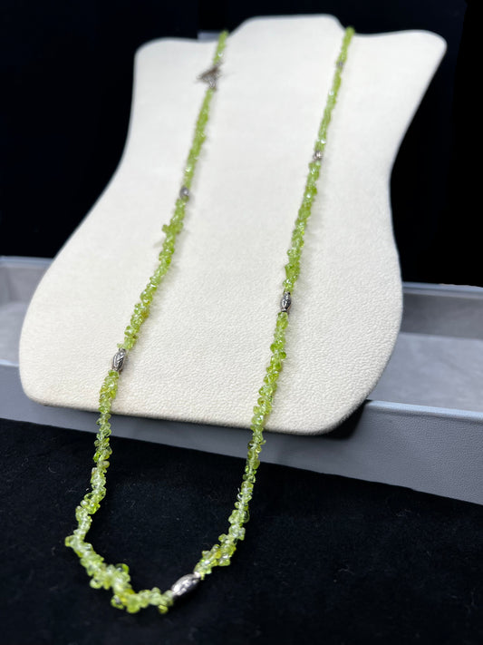 This 36-inch necklace features natural peridot chips expertly strung and paired with sterling silver components. Its vibrant green hues bring a refreshing touch, while sterling silver ensures durability and elegance. Made in India.