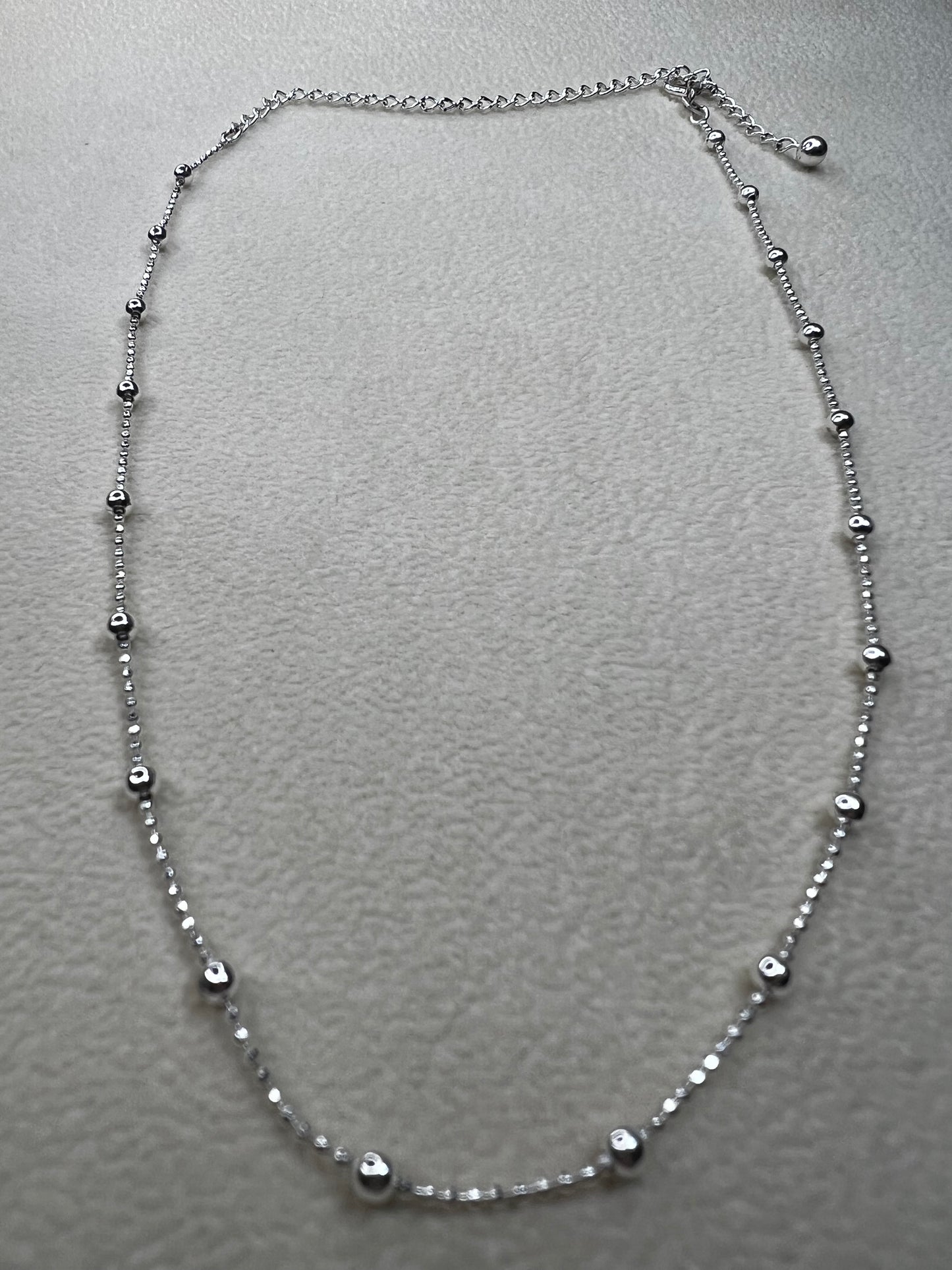 This 15" Italian sterling silver necklace features a bright finish that catches the light beautifully. Its delicate design combines tiny beads with slightly larger spaced beads, creating a simple yet striking accessory that adds subtle elegance to any outfit.
