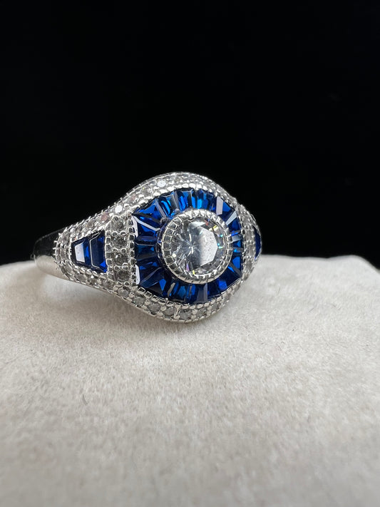 This sterling silver ring showcases exquisite Art Deco design. Featuring captivating blue spinel and quartz stones, it highlights meticulous craftsmanship and a balanced color palette, making it a standout piece for collectors and connoisseurs of fine jewelry. Signed MM.