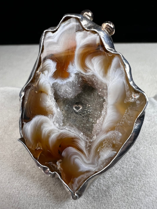 This exquisite ring by Loving Anvil showcases a natural druzy agate slice wrapped in fine sterling silver. Delicately embellished with two small gold accents, the design highlights the stone’s unique open space, creating a one-of-a-kind piece.