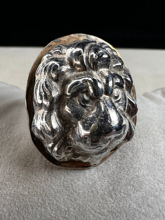 This sterling silver ring by Loving Anvil features a striking lion's head design, expertly crafted for a bold and unique statement. The backing plate is finished in fine gold, adding a stylish two-tone effect.