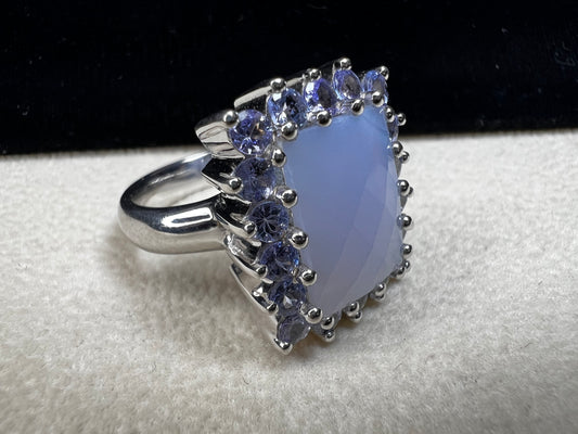 This sterling silver ring combines comfortable wear with captivating style. Featuring a large chalcedony centerpiece surrounded by sparkling tanzanite accent stones, this piece offers a stunning and elegant look.