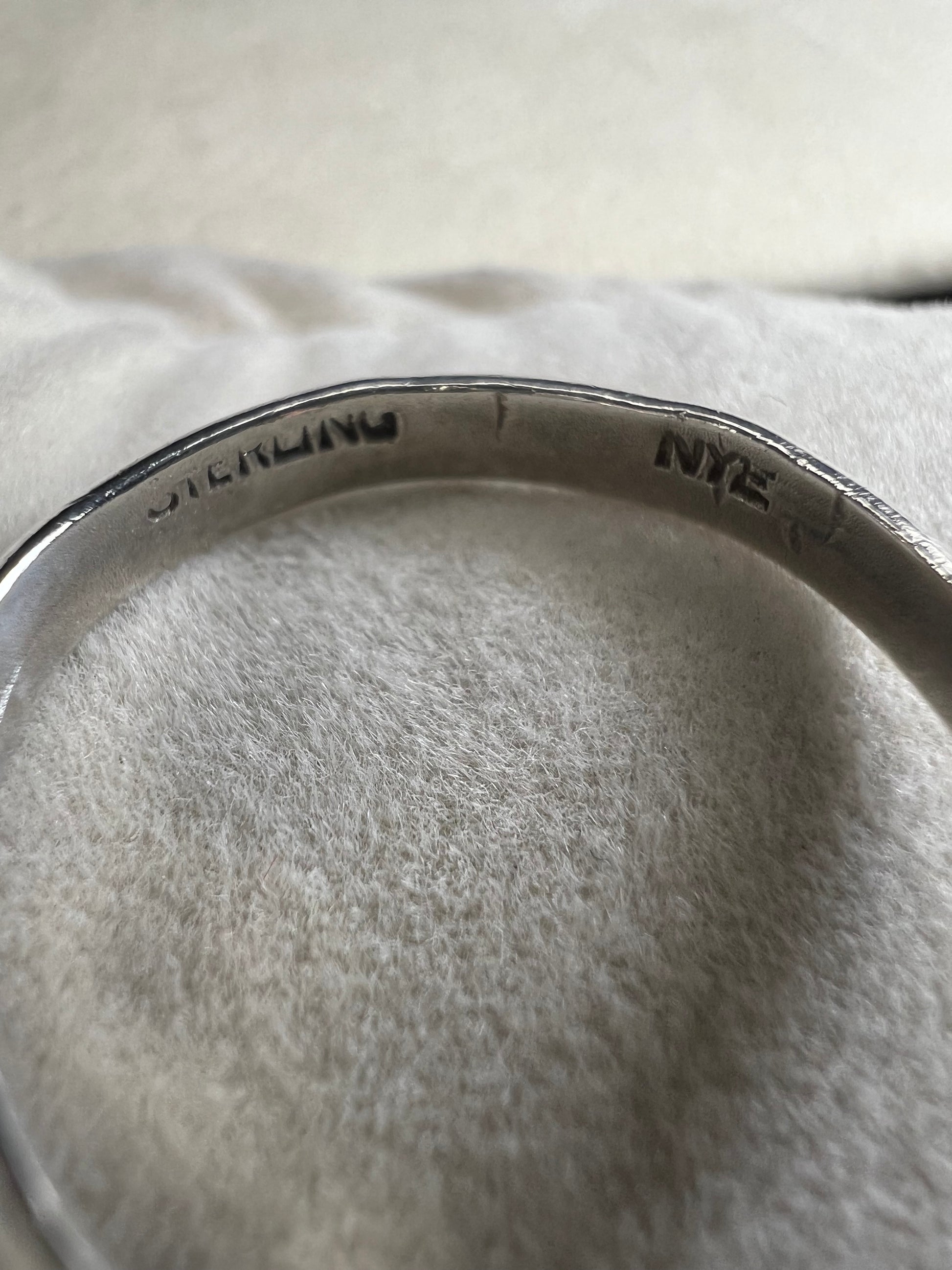 This sterling silver ring by Stuart Nye showcases a delicate dogwood flower design, combining artistry with elegant craftsmanship. Its refined detail makes it a meaningful accessory that adds a touch of nature-inspired beauty to any outfit.