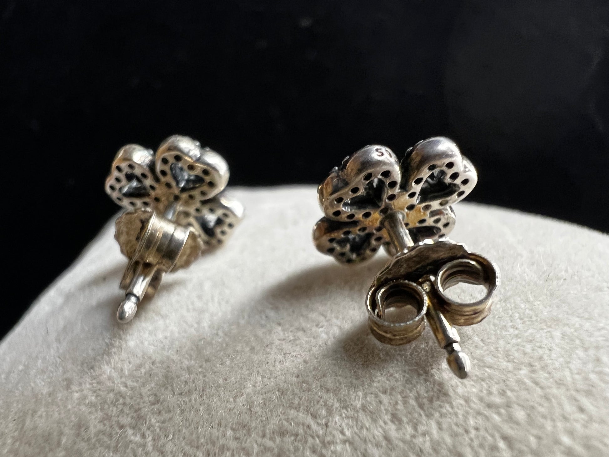 These are beautiful sterling silver earrings. They are shaped as four-leaf clovers with heart designs in each leaf and set with small clear stones throughout.