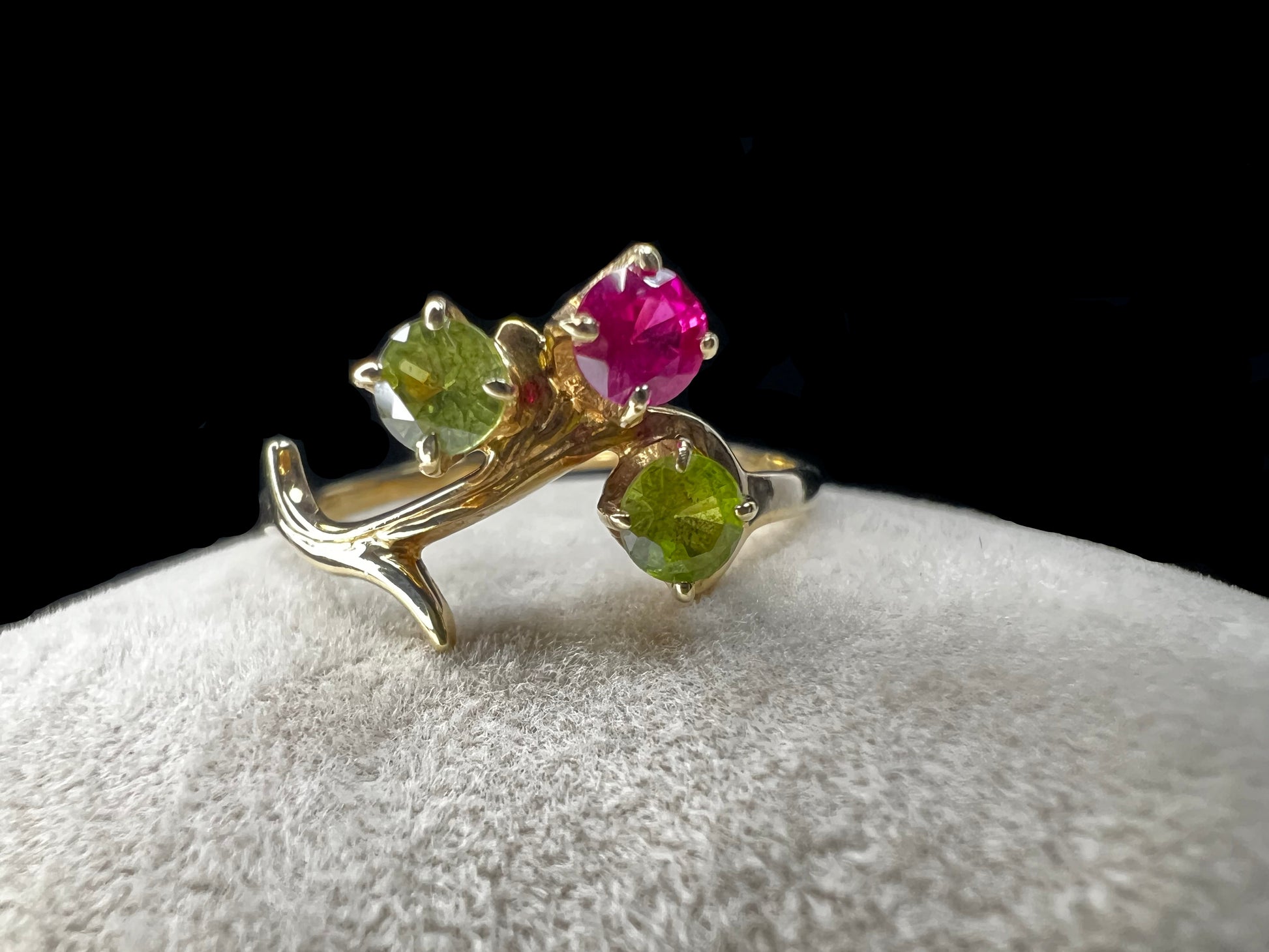 Crafted from 10 karat gold and designed to look like a tree branch, this ring is set with two spinels and a ruby.