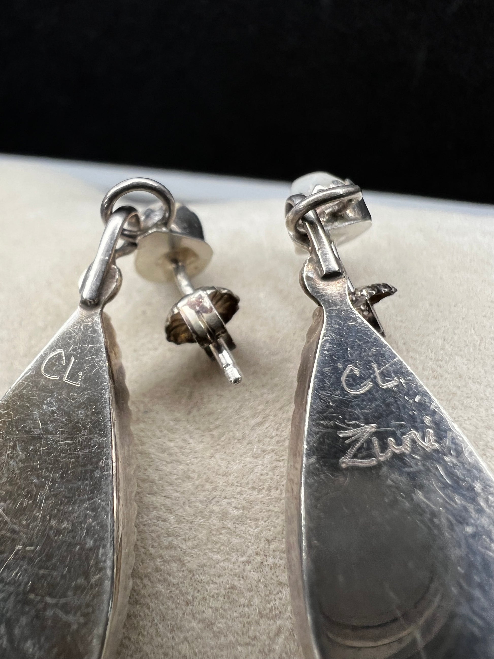 These handmade Zuni sterling silver earrings feature raised turquoise flowers set over luminous mother of pearl. Signed CL Zuni, these teardrop earrings showcase traditional Native American artistry with beautiful depth and dimension.