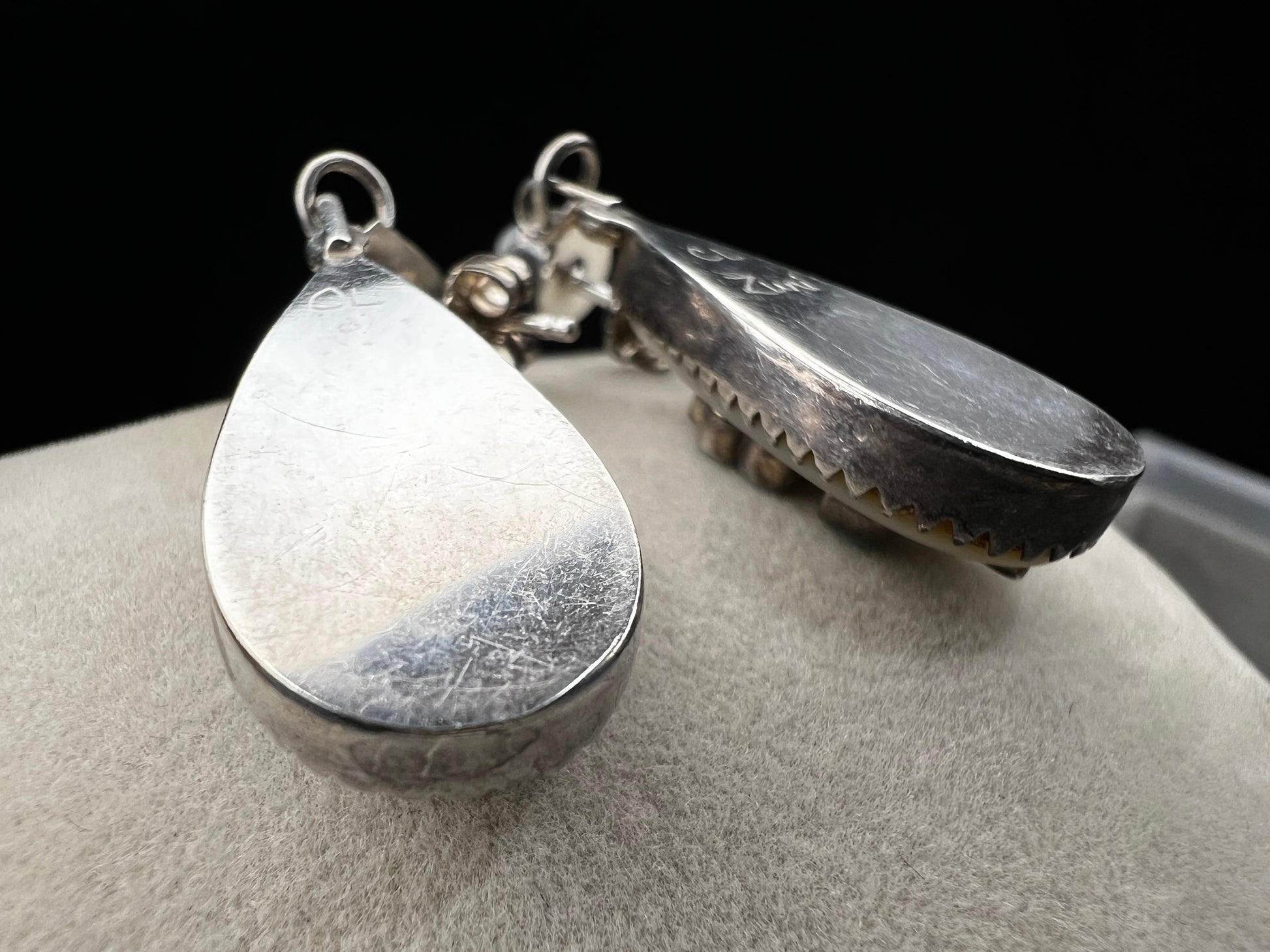 These handmade Zuni sterling silver earrings feature raised turquoise flowers set over luminous mother of pearl. Signed CL Zuni, these teardrop earrings showcase traditional Native American artistry with beautiful depth and dimension.