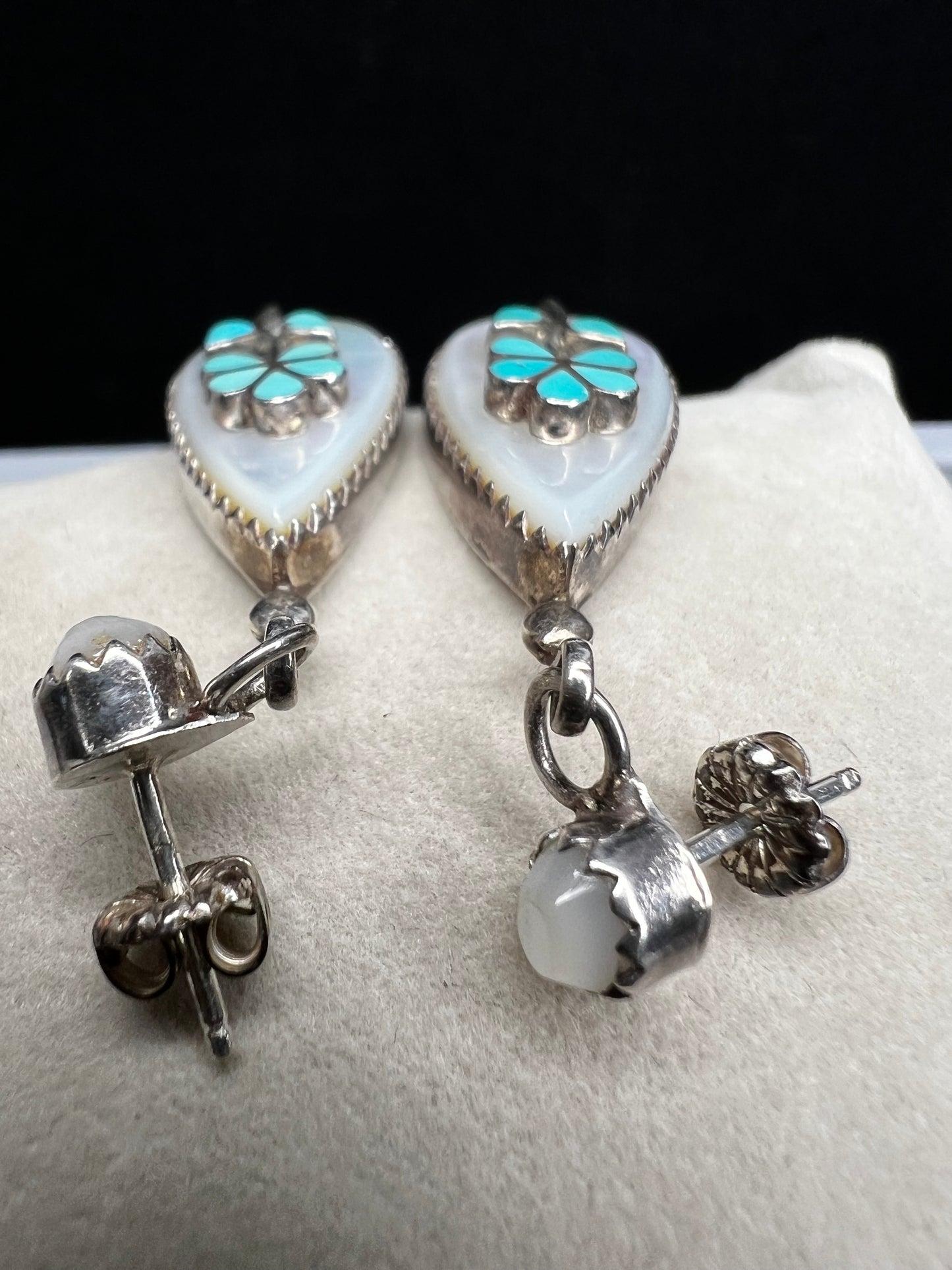 These handmade Zuni sterling silver earrings feature raised turquoise flowers set over luminous mother of pearl. Signed CL Zuni, these teardrop earrings showcase traditional Native American artistry with beautiful depth and dimension.