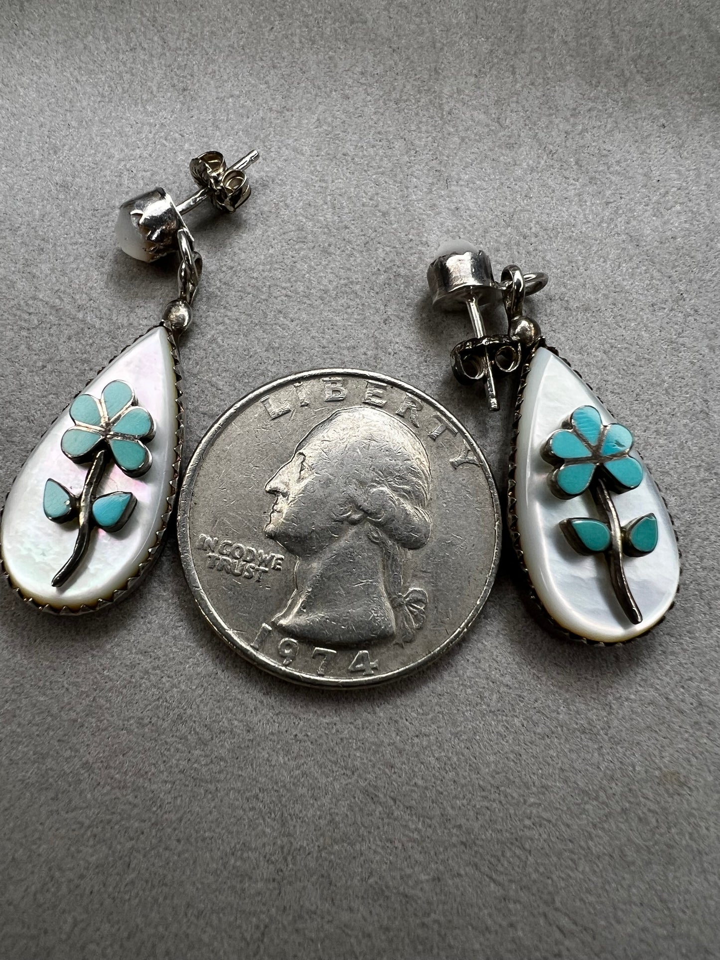 These handmade Zuni sterling silver earrings feature raised turquoise flowers set over luminous mother of pearl. Signed CL Zuni, these teardrop earrings showcase traditional Native American artistry with beautiful depth and dimension.