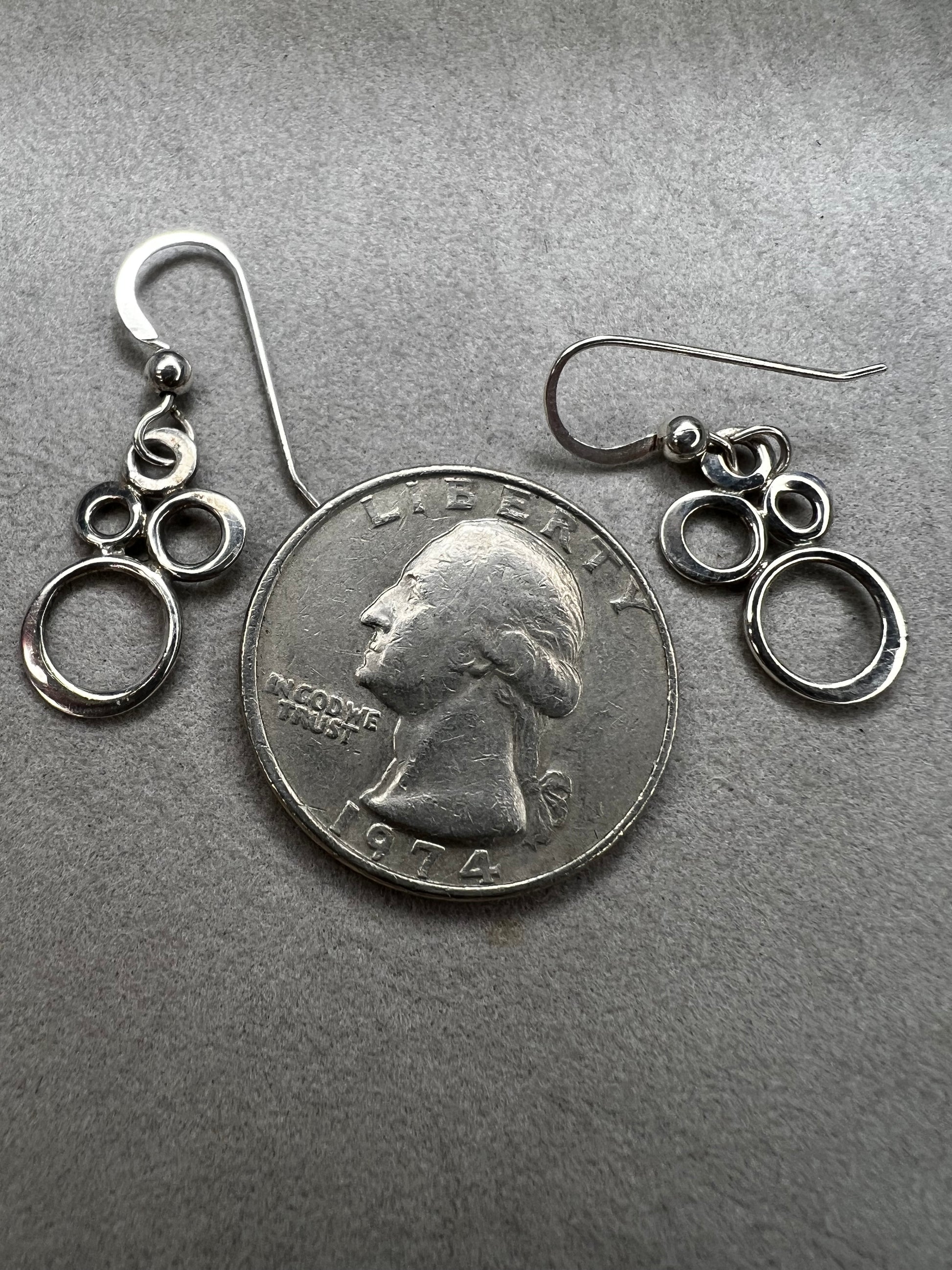 These elegant sterling silver dangle earrings feature an eye-catching arrangement of circles in varying sizes, creating a playful yet minimalist look.