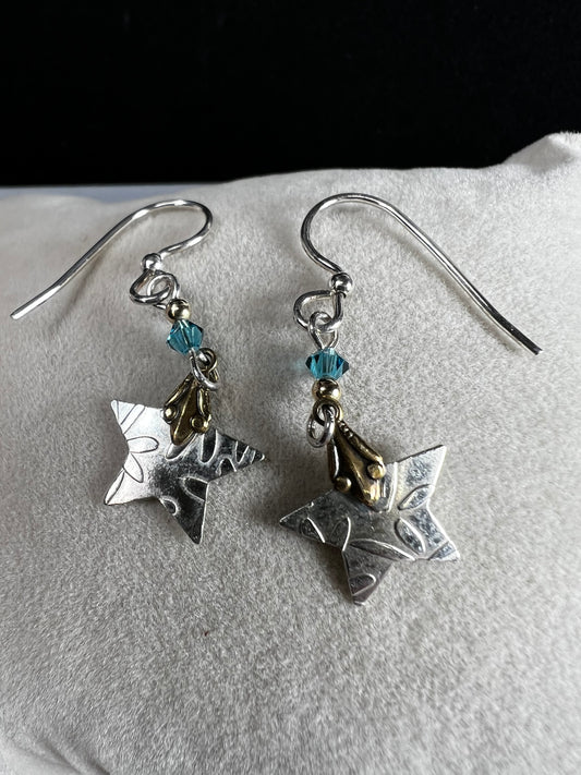 These sterling silver earrings are accented with 14-karat gold, creating a two-toned design as the stars dance in the light.
