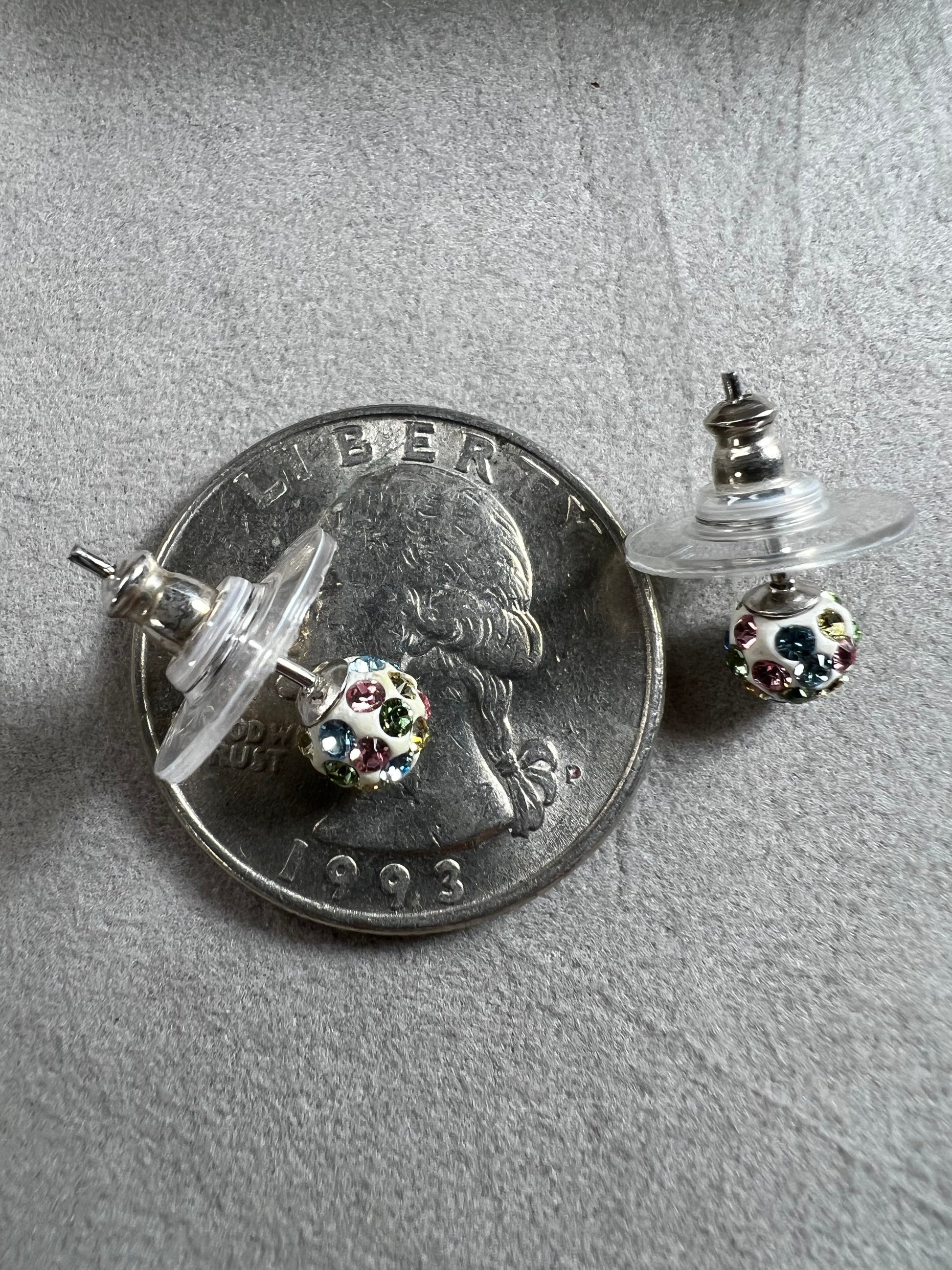 Crafted from sterling silver, these stud earrings are detailed with white enamel and sprinkled with crystals in a variety of colors that create a vibrant sparkle.