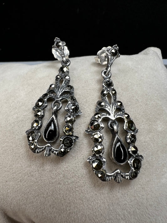 These sterling silver earrings shimmer with marcasite accents and showcase a dangling teardrop of onyx, adding timeless charm and subtle movement.