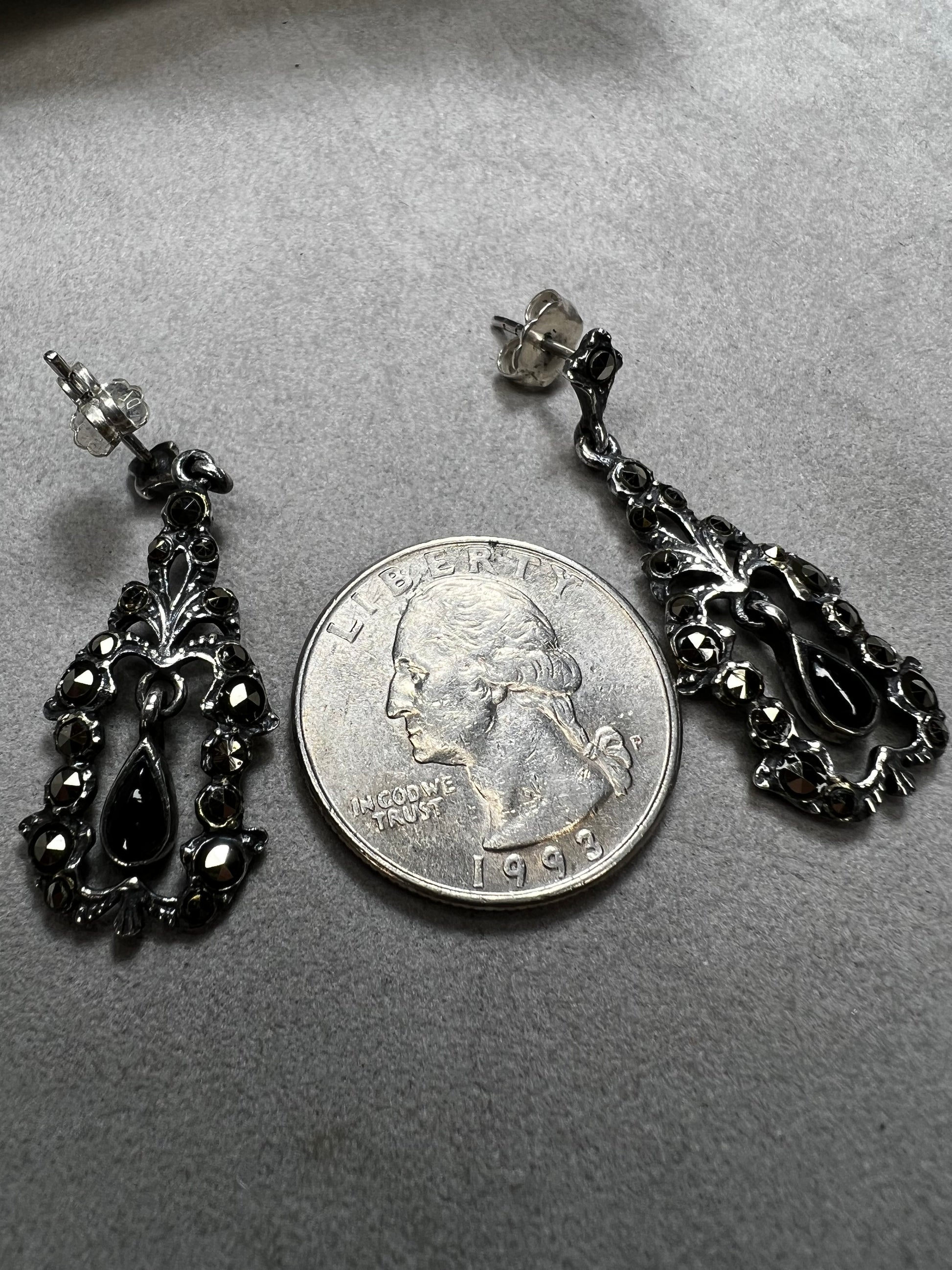 These sterling silver earrings shimmer with marcasite accents and showcase a dangling teardrop of onyx, adding timeless charm and subtle movement.