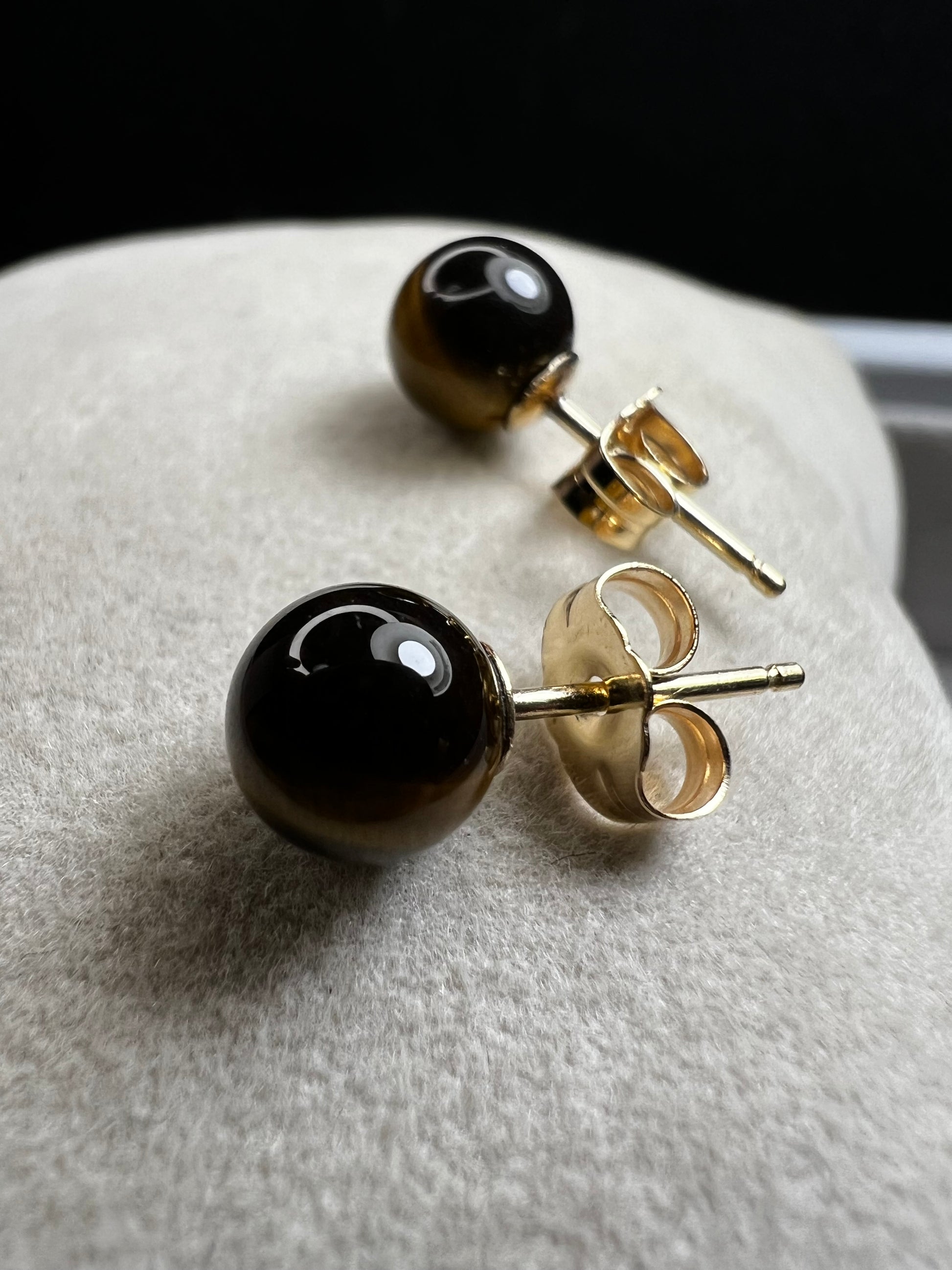 These earrings are crafted with 14 karat gold and feature a beautiful, petite tiger's eye stone.