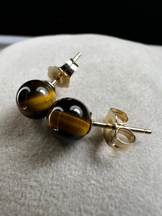 These earrings are crafted with 14 karat gold and feature a beautiful, petite tiger's eye stone.