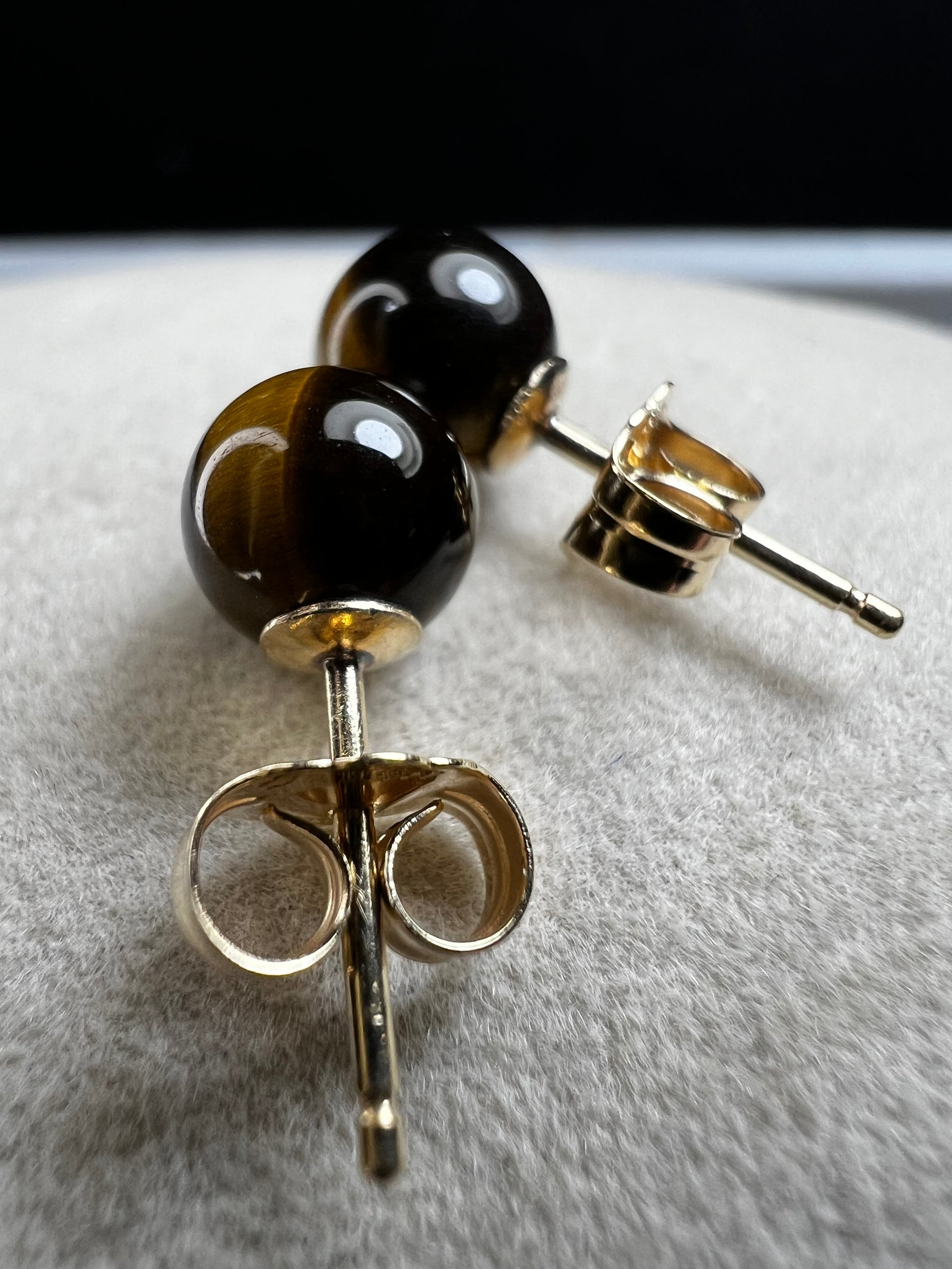 These earrings are crafted with 14 karat gold and feature a beautiful, petite tiger's eye stone.