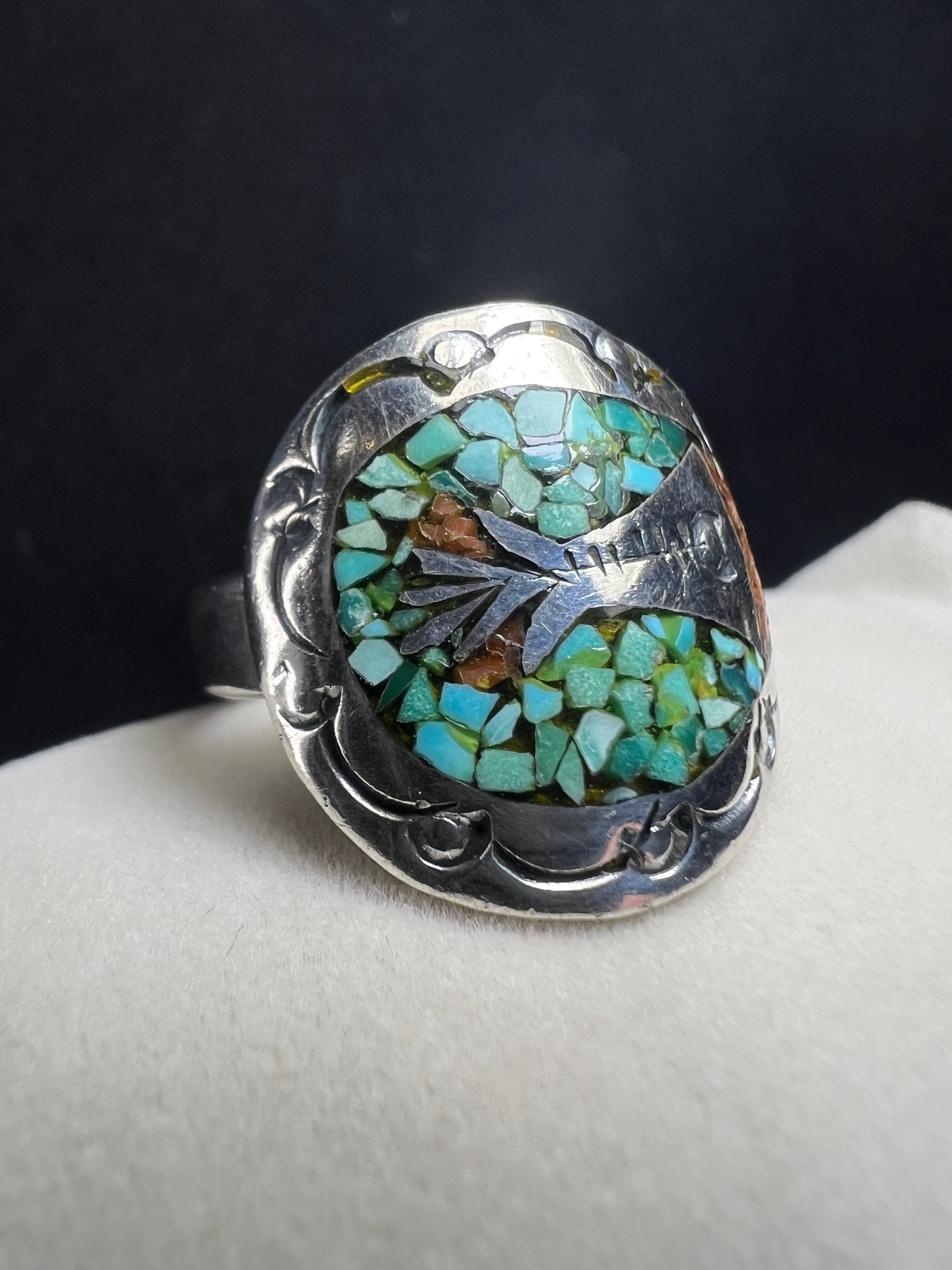 This expertly crafted vintage sterling silver ring, signed LB, showcases intricate detailing that captures timeless elegance. Accented with turquoise chips, it offers a distinctive and striking look, perfect for collectors or anyone seeking a unique piece with authentic vintage charm.