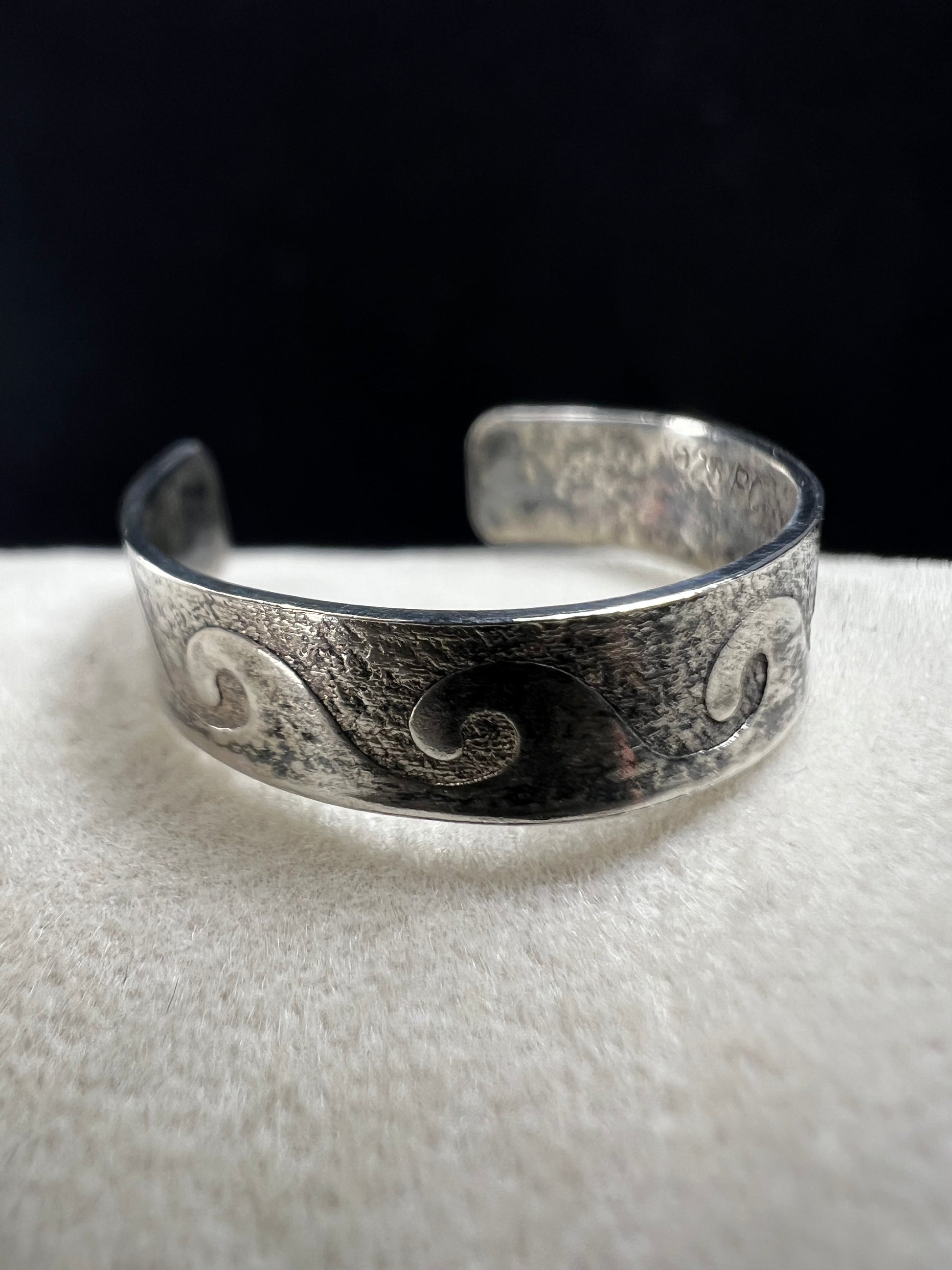 This vintage sterling silver toe ring features an open band with a timeless wave design, ideal for beach enthusiasts. Its detailed craftsmanship captures the effortless spirit of the ocean, making it a refined accessory for seaside or casual wear.