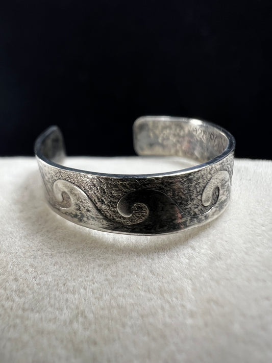 This vintage sterling silver toe ring features an open band with a timeless wave design, ideal for beach enthusiasts. Its detailed craftsmanship captures the effortless spirit of the ocean, making it a refined accessory for seaside or casual wear.