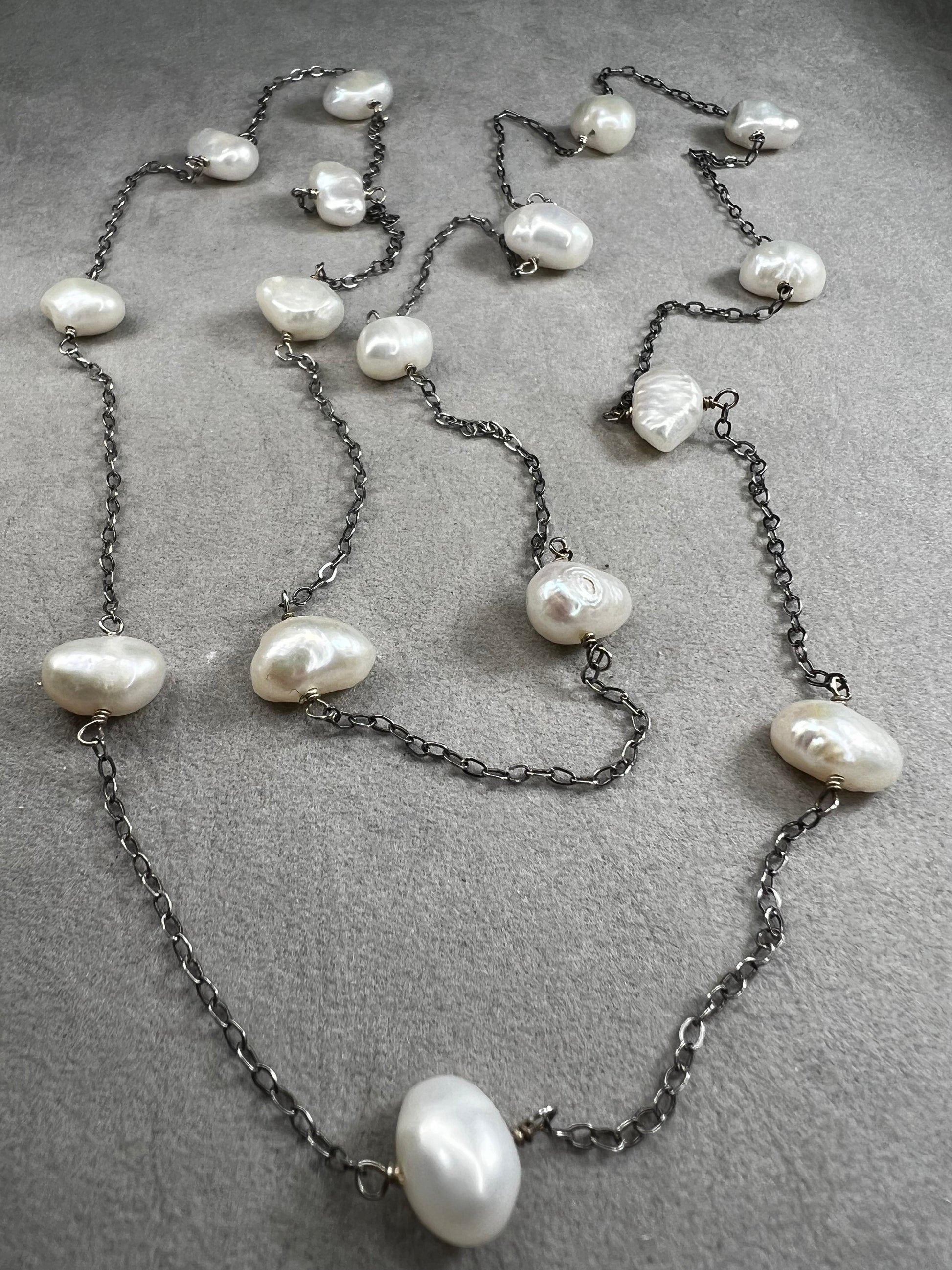 This 34-inch sterling silver chain is accented with baroque pearls spaced a few inches apart. Designed without a clasp, it slips easily over your head for effortless wear.