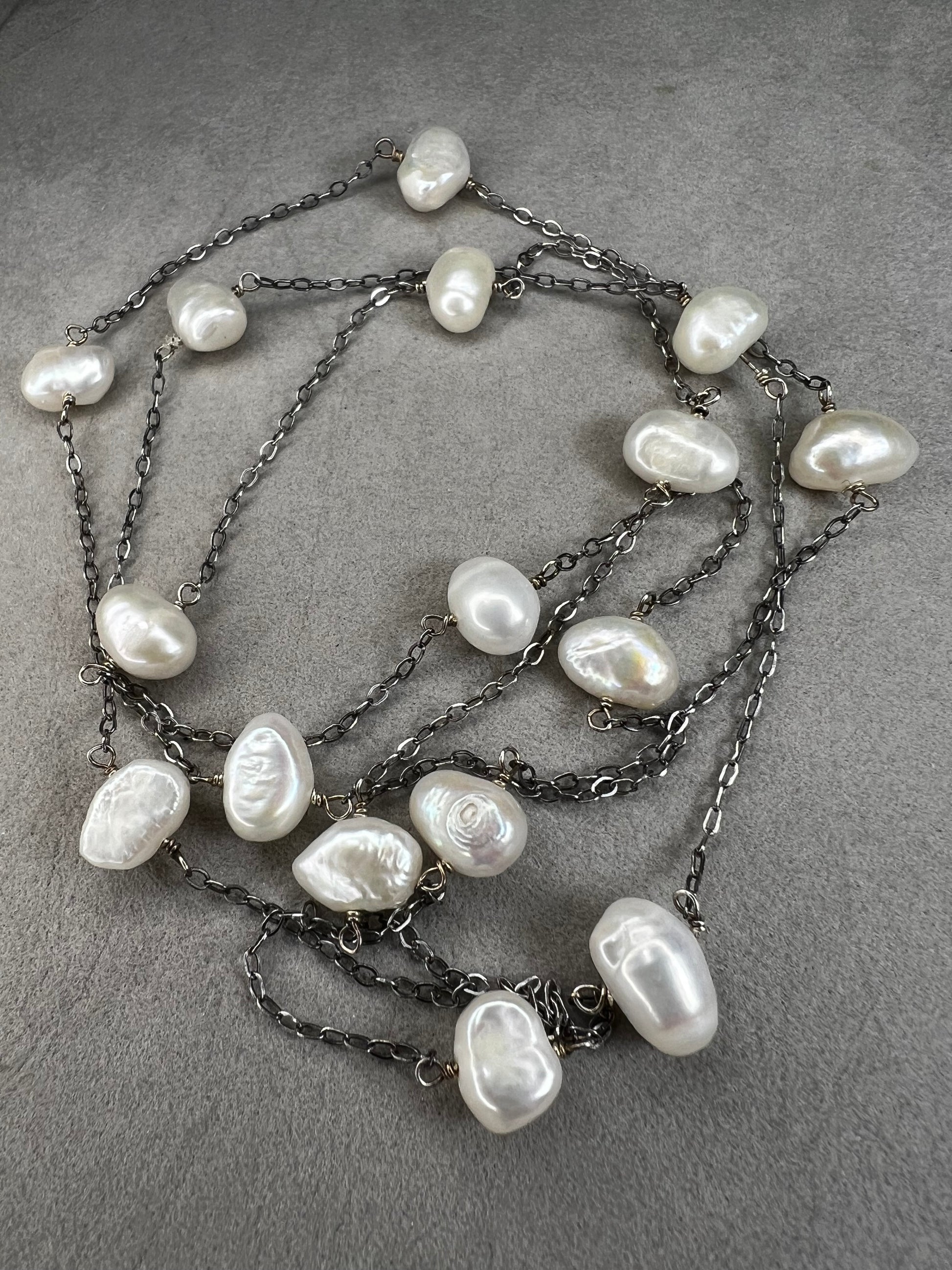 This 34-inch sterling silver chain is accented with baroque pearls spaced a few inches apart. Designed without a clasp, it slips easily over your head for effortless wear.