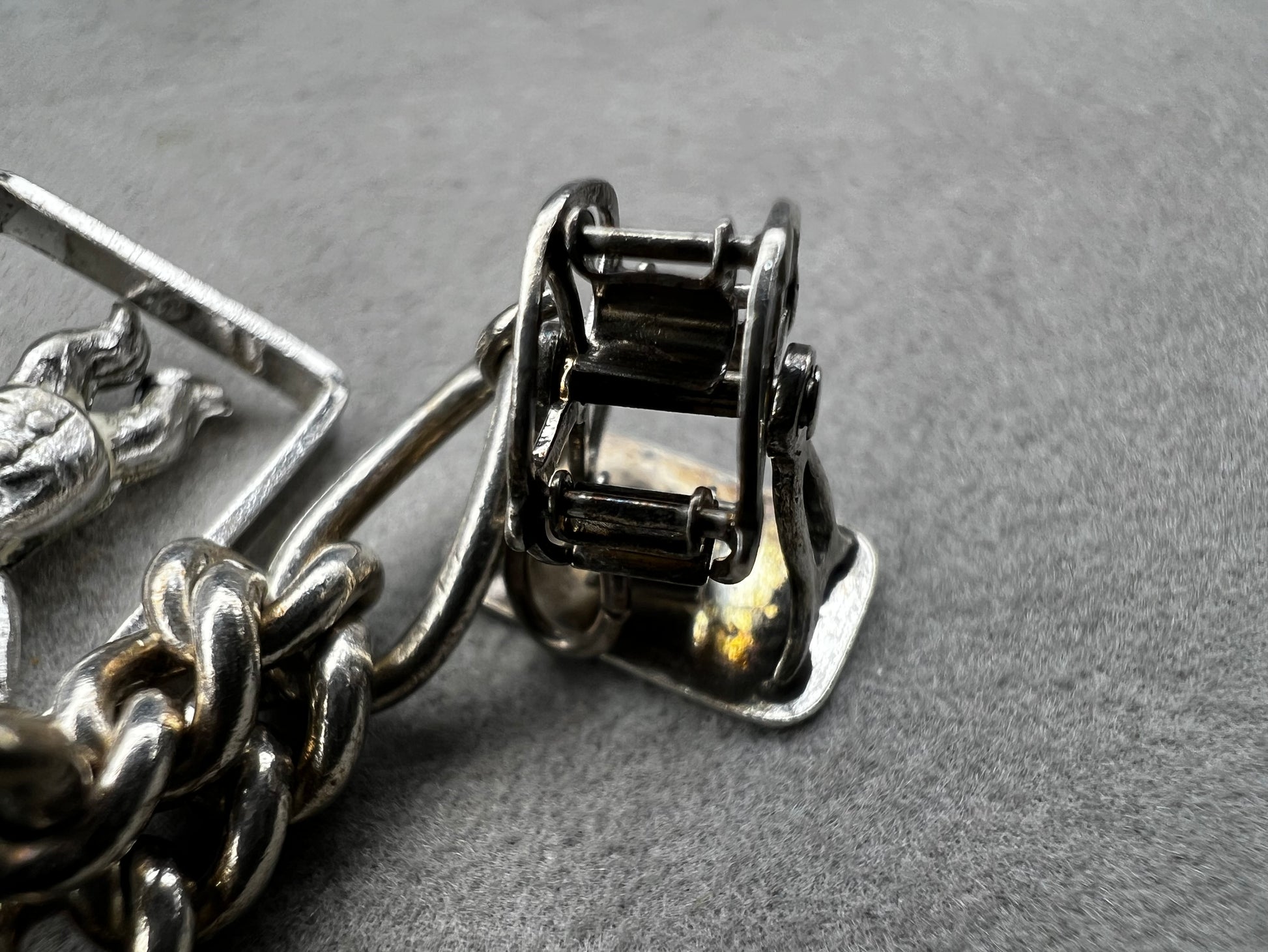This 1940s sterling silver bracelet features four articulated charms: a Ferris wheel, a gymnastics clown, the old woman in a shoe, and a lighter. Each charm is finely crafted, showcasing detailed workmanship characteristic of the era.