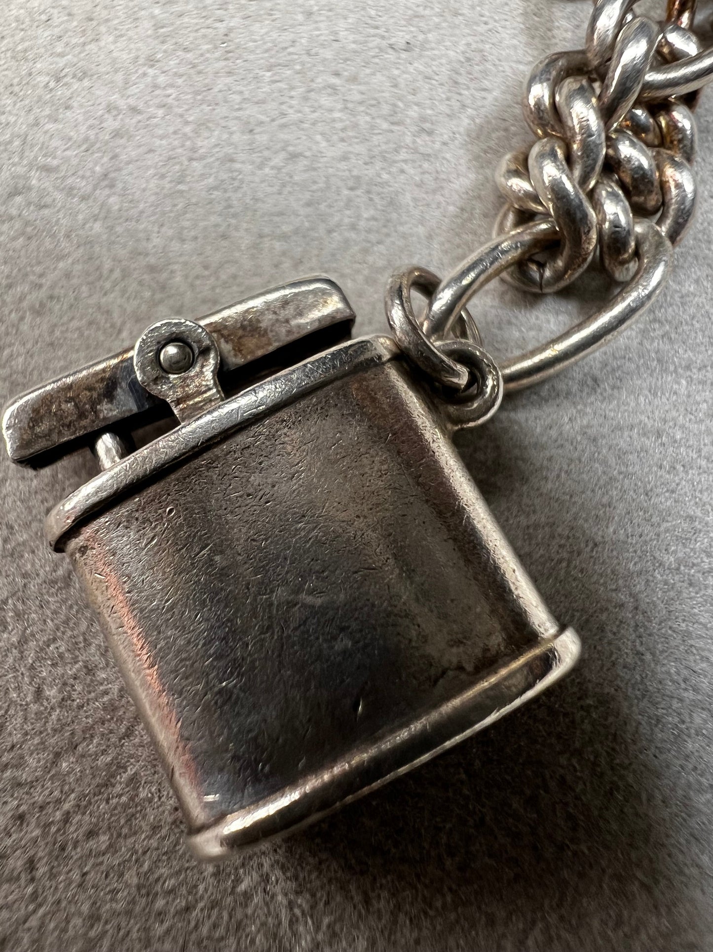 This 1940s sterling silver bracelet features four articulated charms: a Ferris wheel, a gymnastics clown, the old woman in a shoe, and a lighter. Each charm is finely crafted, showcasing detailed workmanship characteristic of the era.