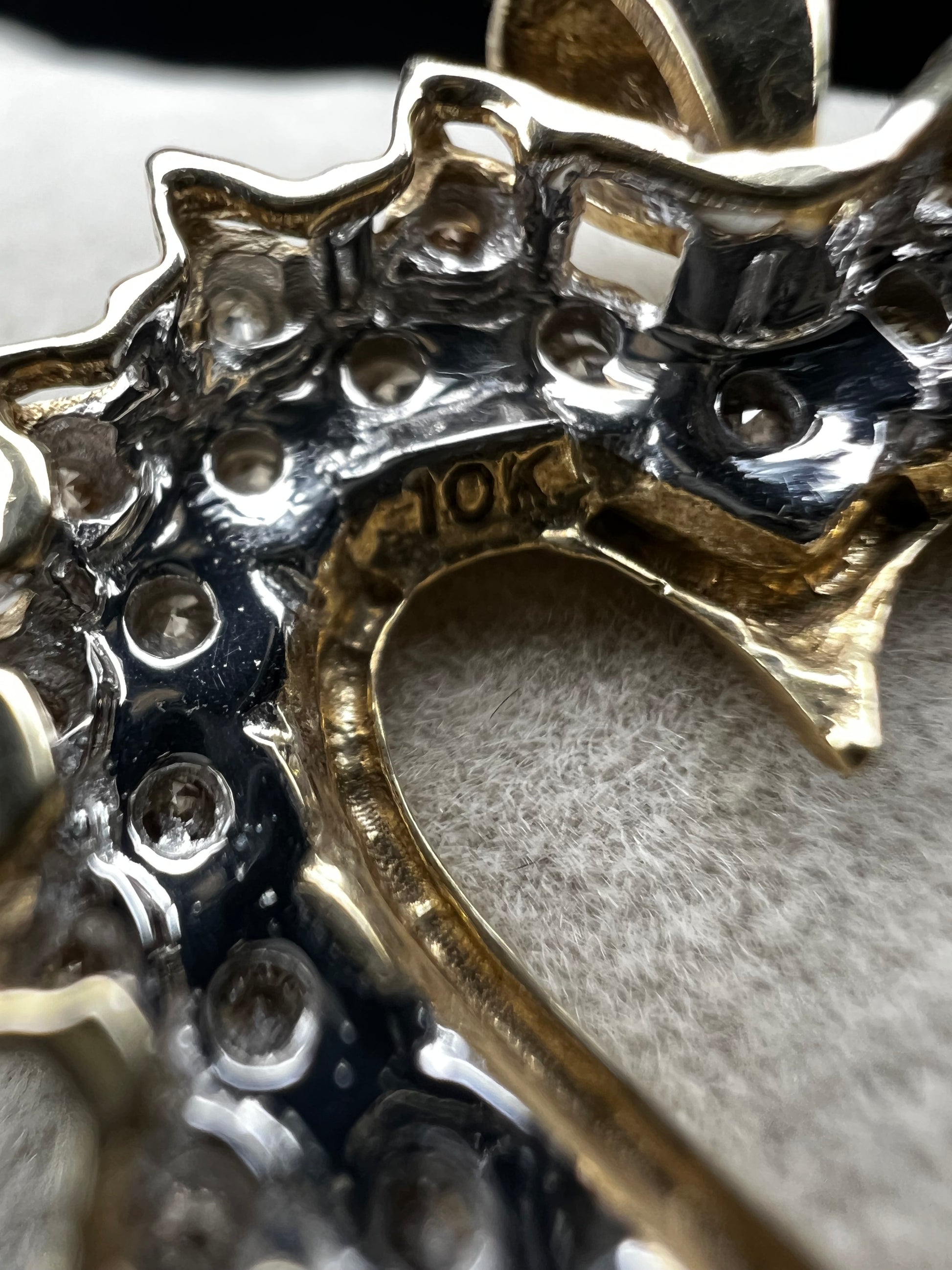 This heart-shaped pendant is crafted with 10 karat yellow gold with a bright white finish around the top to accentuate dazzling natural diamonds that cover the face of this piece.